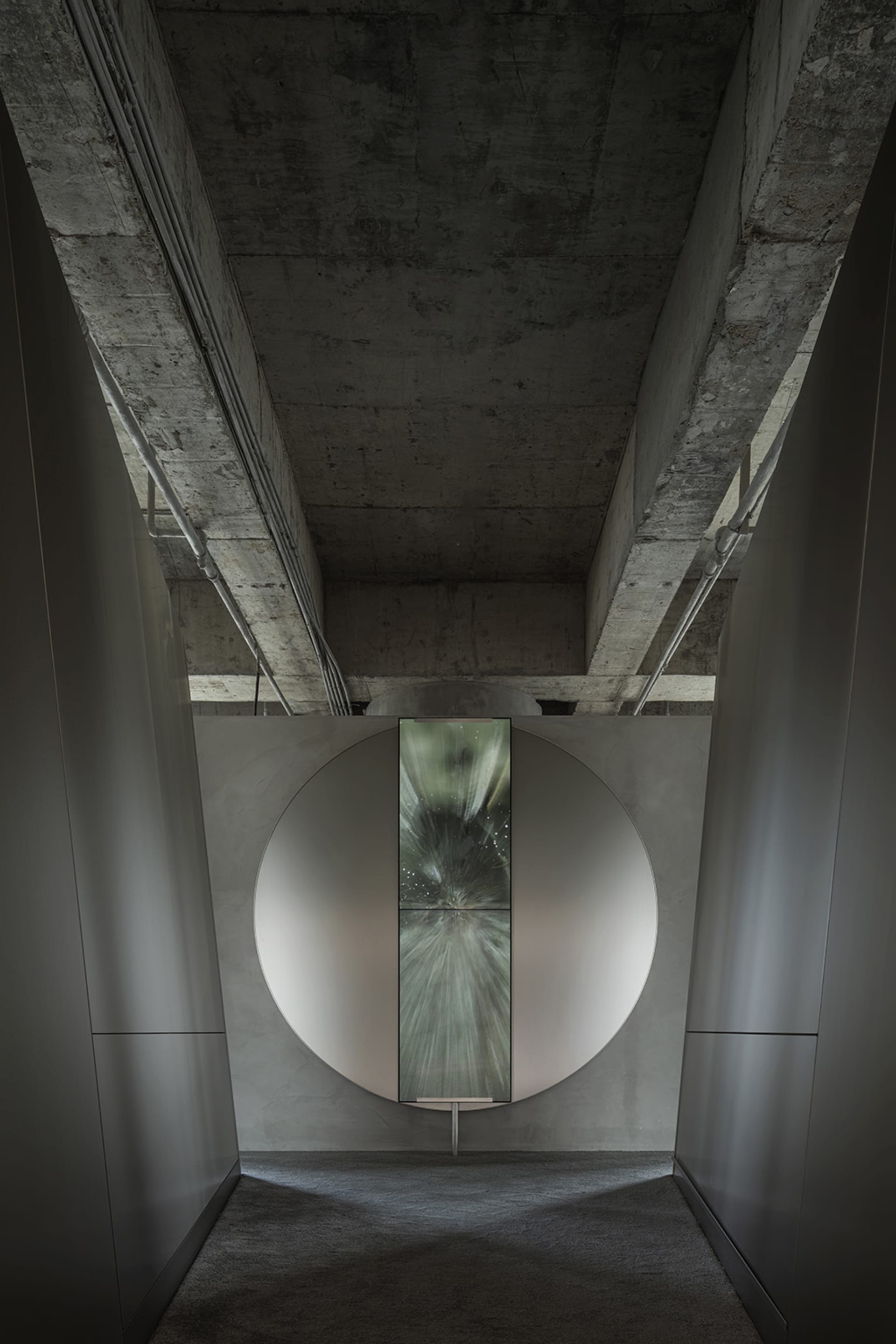 Modern lobby with a circular concrete wall and a glass panel on the ceiling.