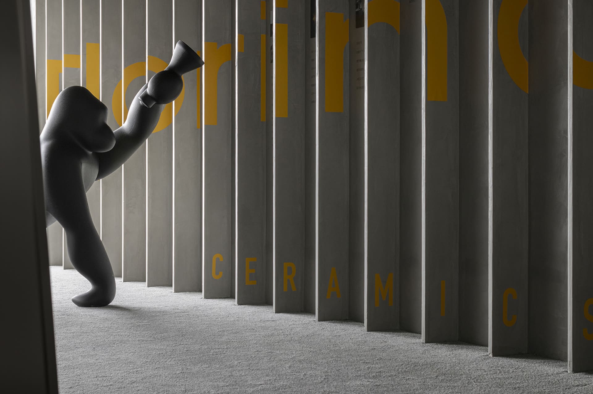 A modern ceramic object displayed against a grey, concrete wall with yellow text reading "ceramics."