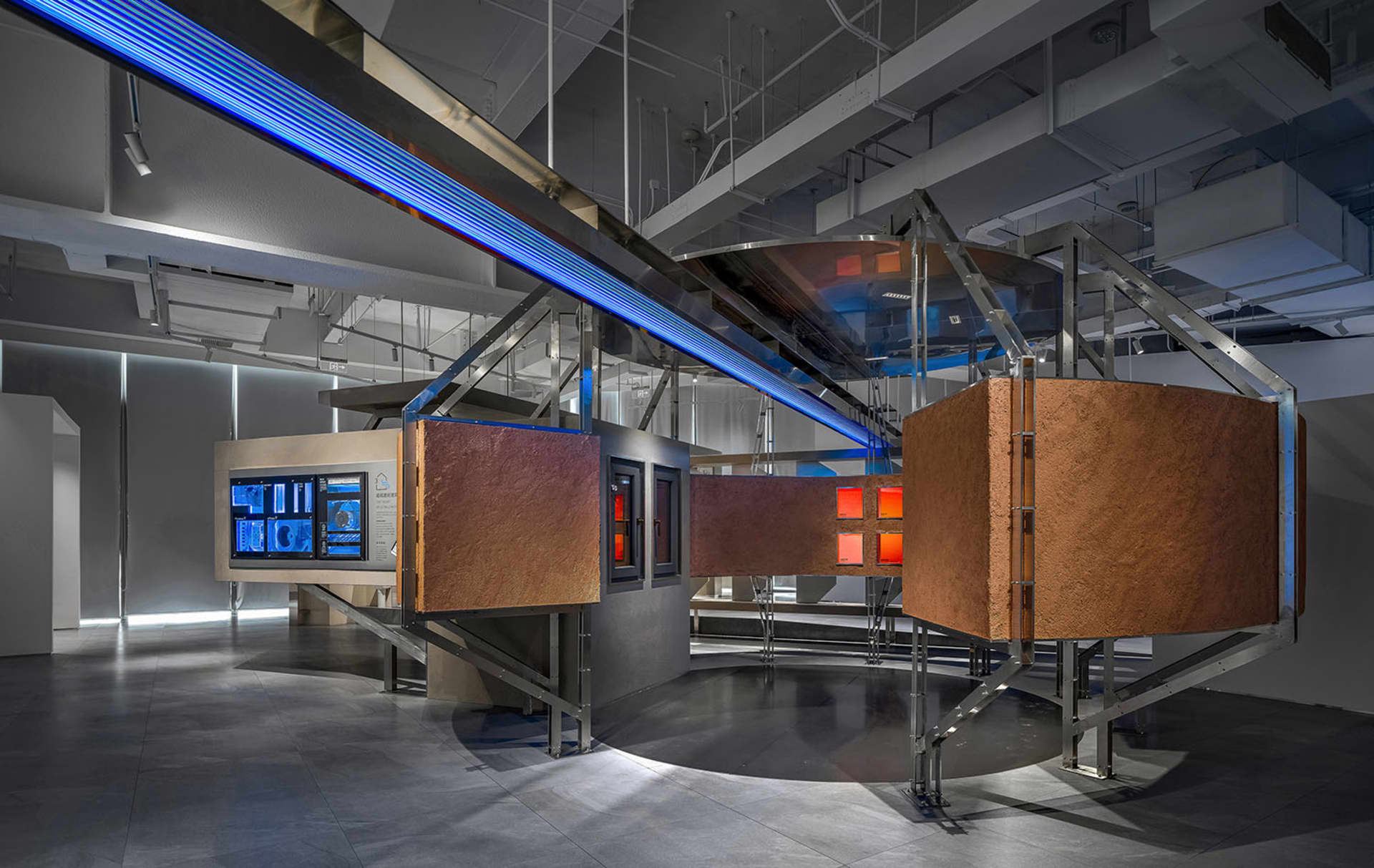 Industrial-style exhibition space featuring metal, glass, and wooden elements.