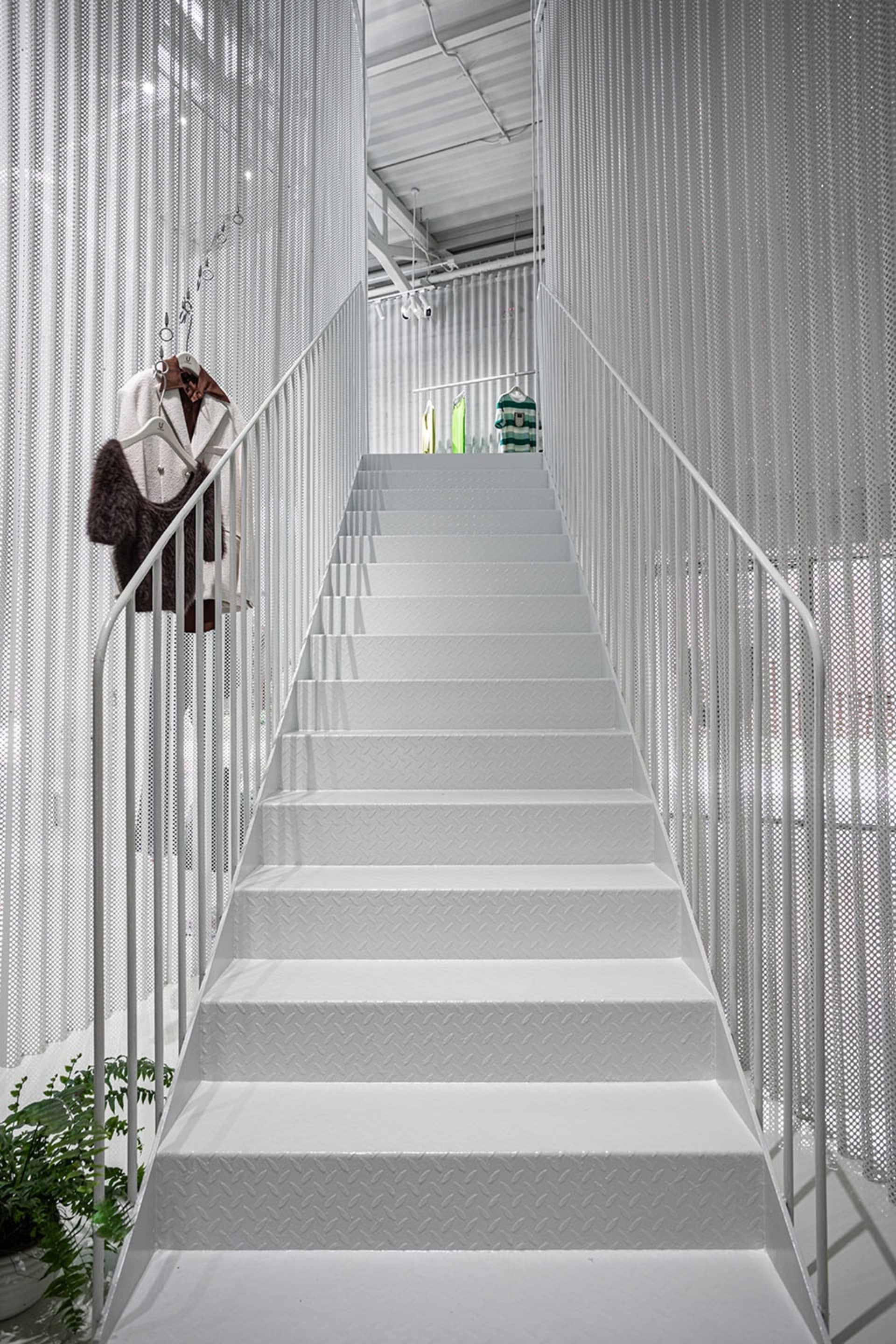 Modern interior design featuring metallic stairs with white walls and railings