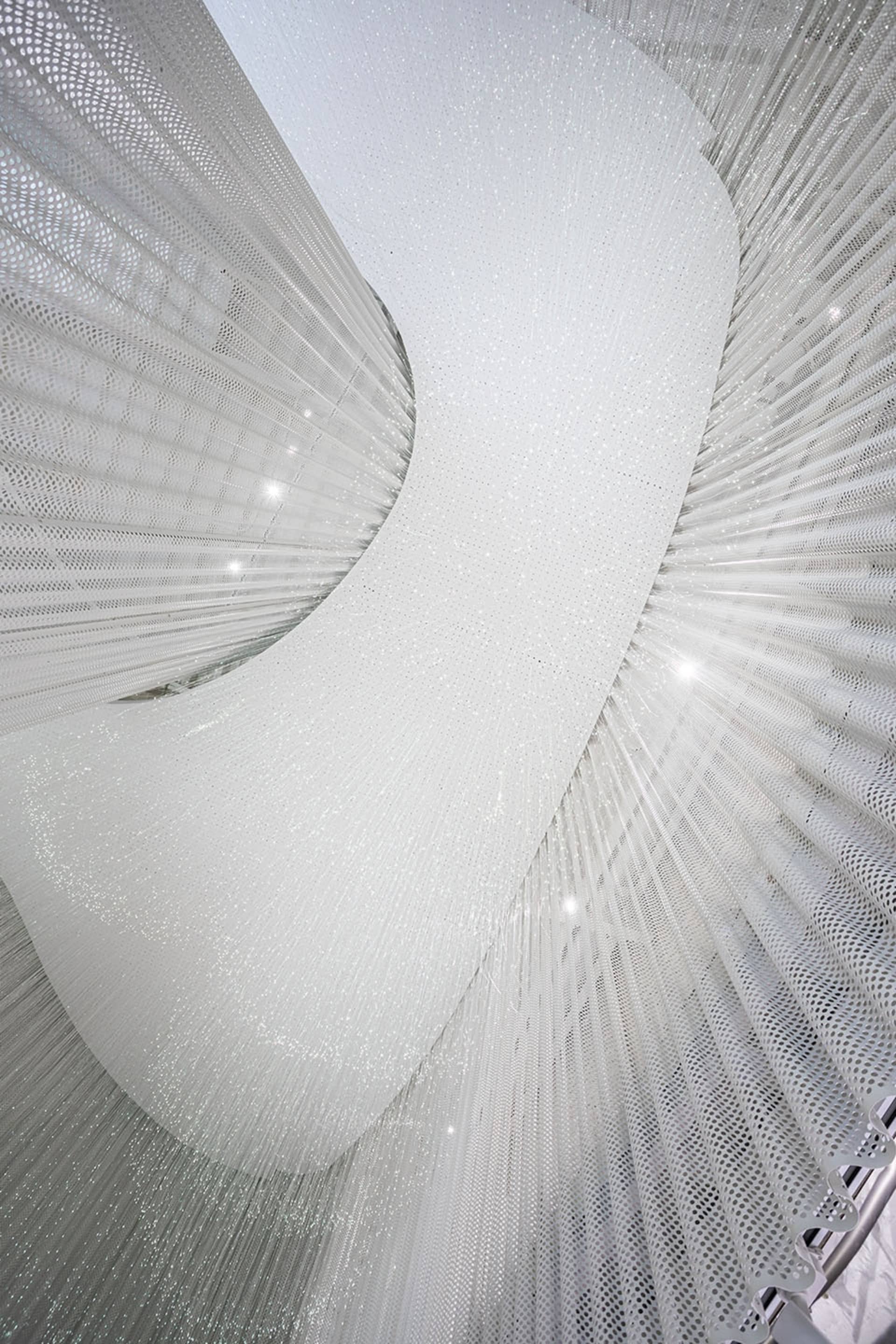 A modern textile lighting installation featuring soft, white light and intricate, cylindrical shapes.