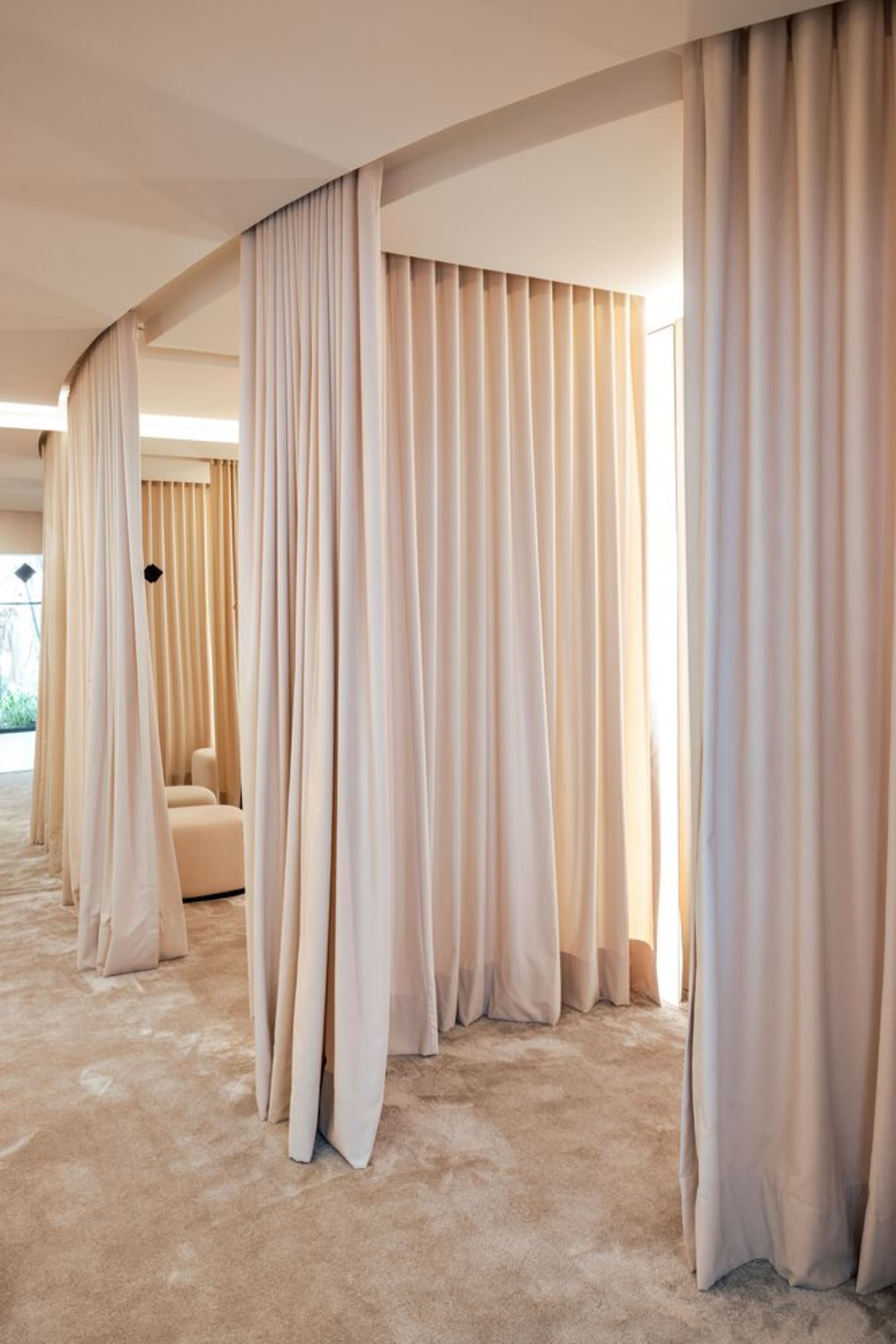 A modern minimalist interior featuring space-partitioning curtains made of fabric.