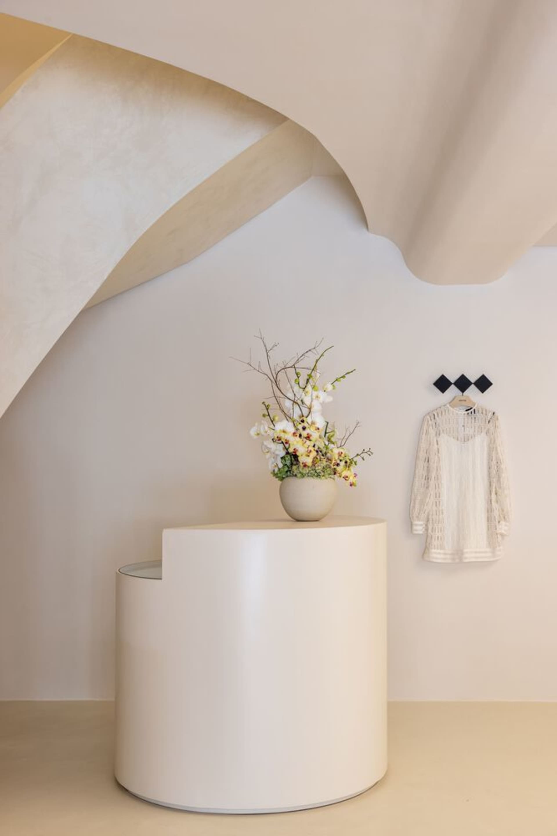 A minimalist modern space with white cylindrical objects and floral arrangement.