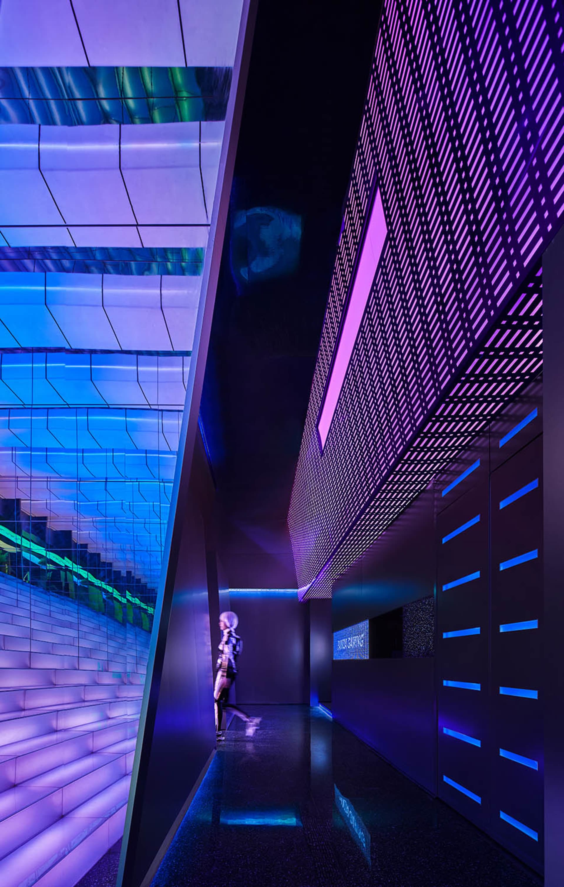 A modern interior space featuring glass walls and a geometric design with vibrant lighting.