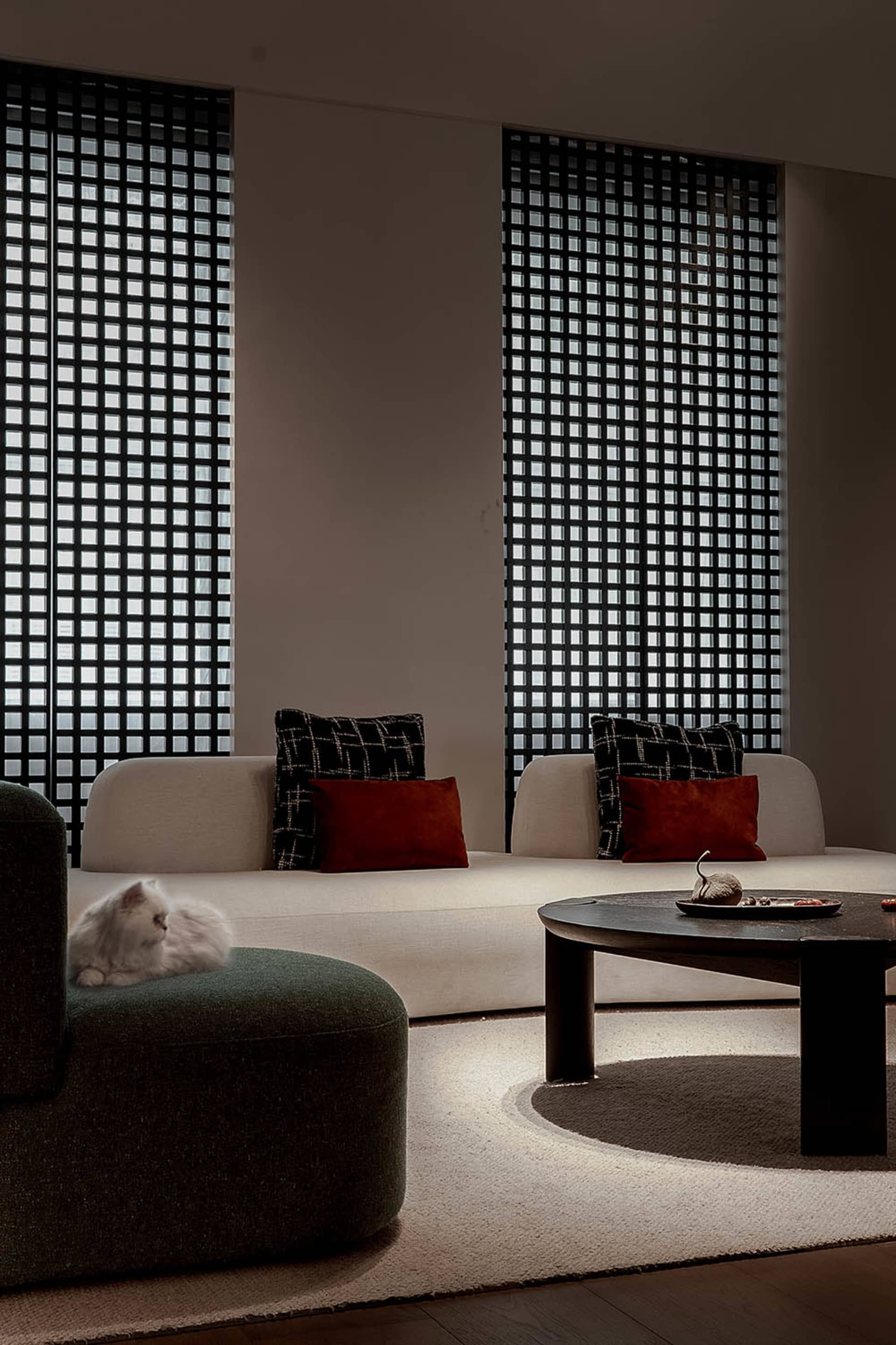 A modern living room with a white sofa, patterned cushions, and a round wooden coffee table.
