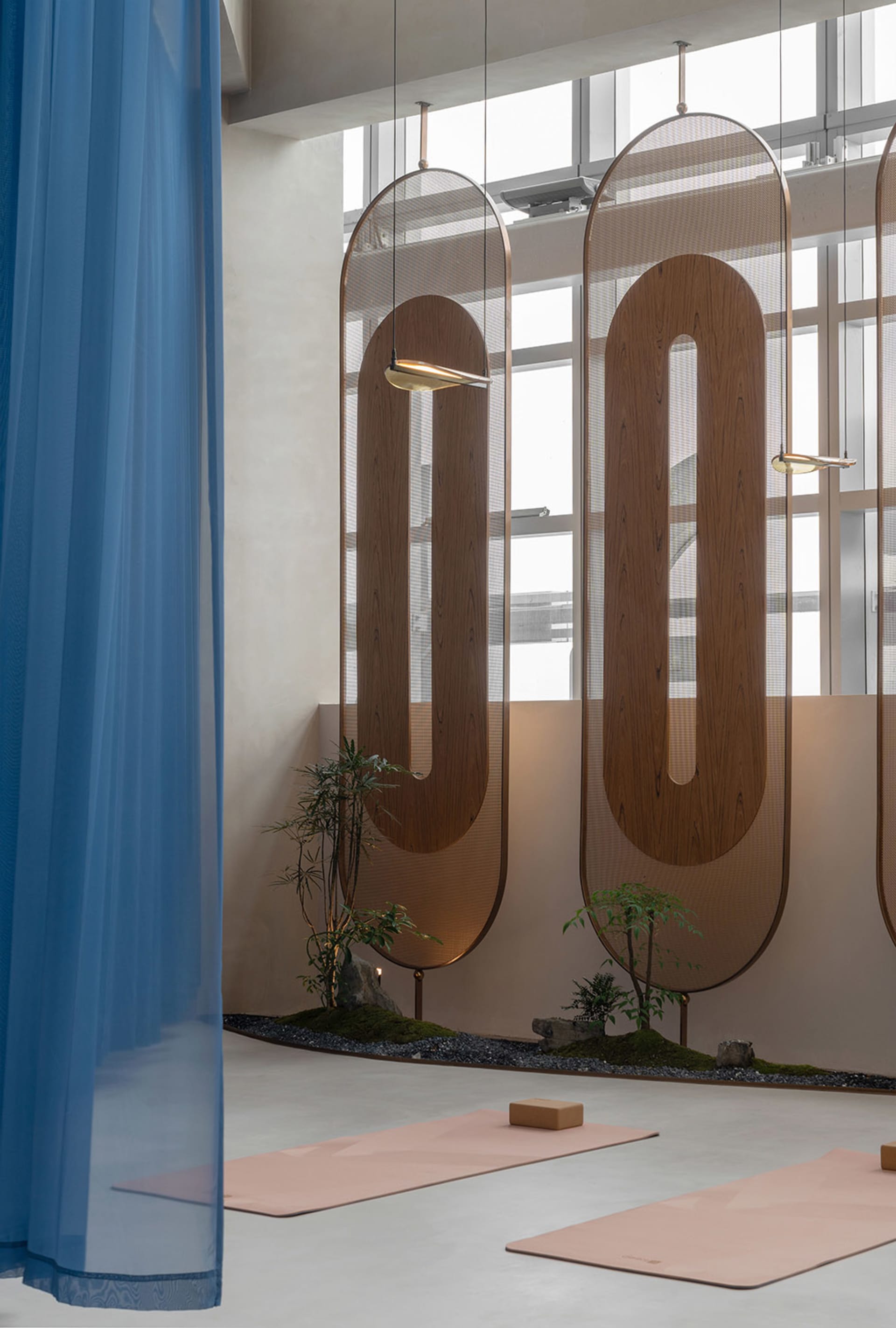 A minimalist spa yoga room featuring wooden elements such as mats, planters, and screens.