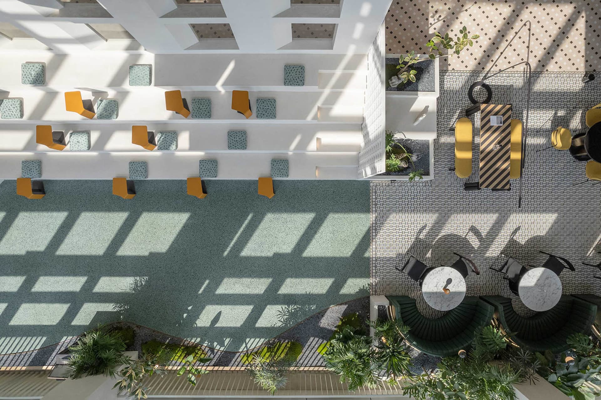 A modern cafe interior with a terrazzo floor plan featuring a mixture of white and green tiles, and yellow and black chairs.