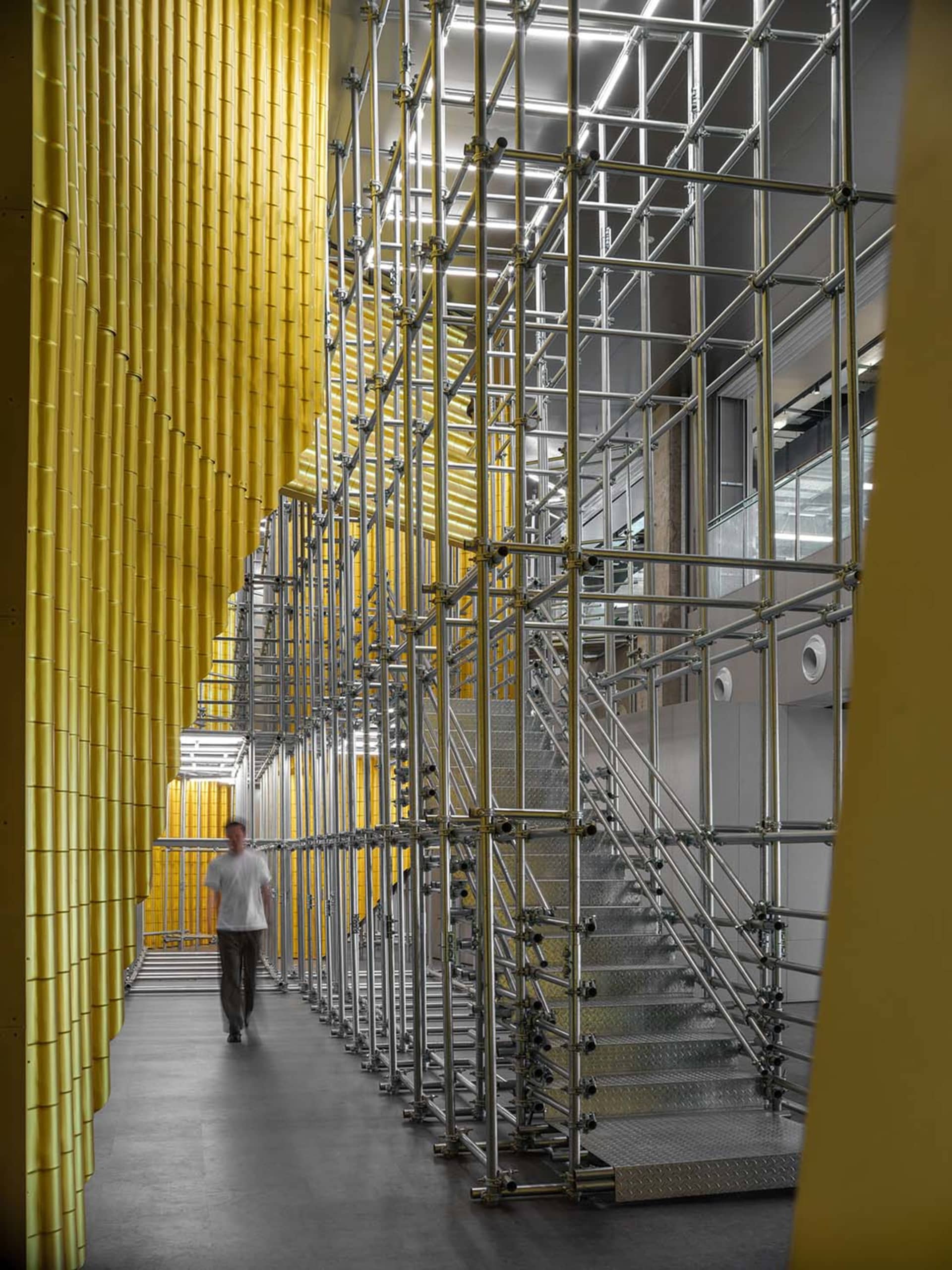 Industrial-style interior design featuring a metal scaffold structure and yellow panel walls