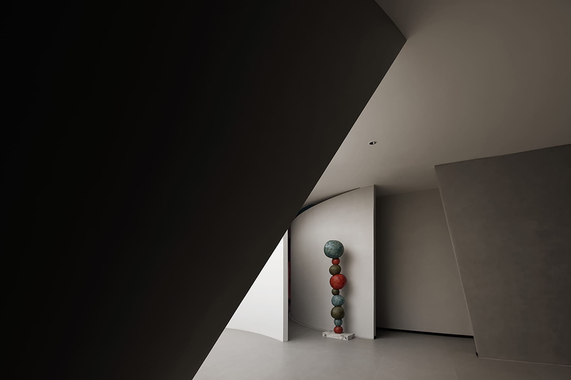 A modern interior space featuring a sculpture made of stacked, multicolored spheres on a pedestal.