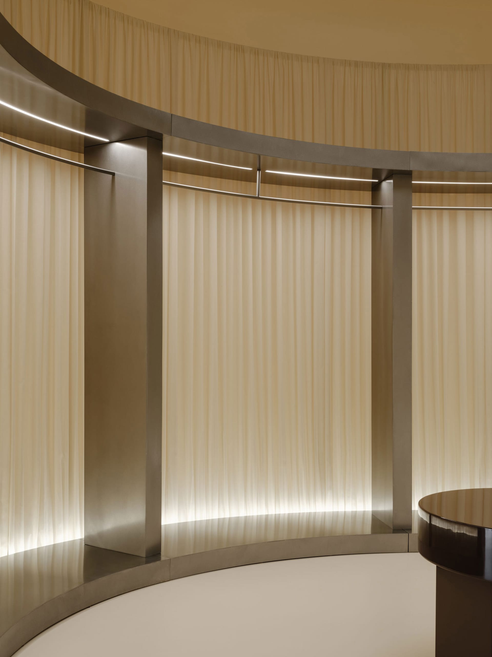 A minimalist interior design featuring curtains made of a soft, flowing textile material.