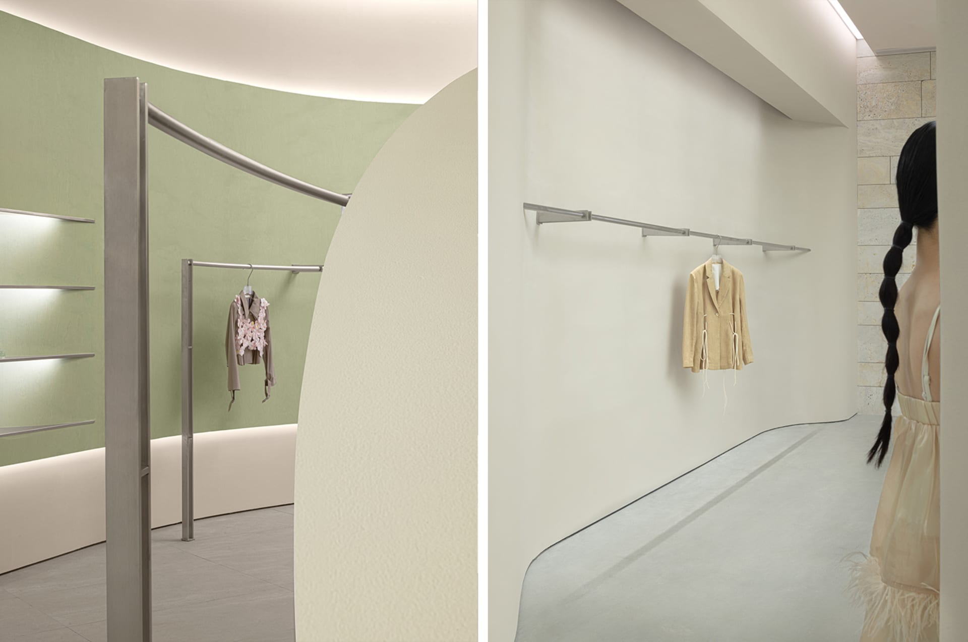 A minimalist retail display featuring metal rails mounted on a plain white wall, showcasing a single jacket.