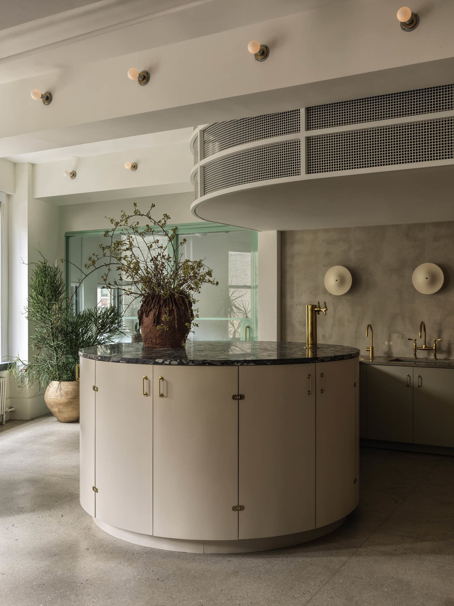 Modern kitchen with marble countertops and cabinets, featuring a central island and industrial lighting.