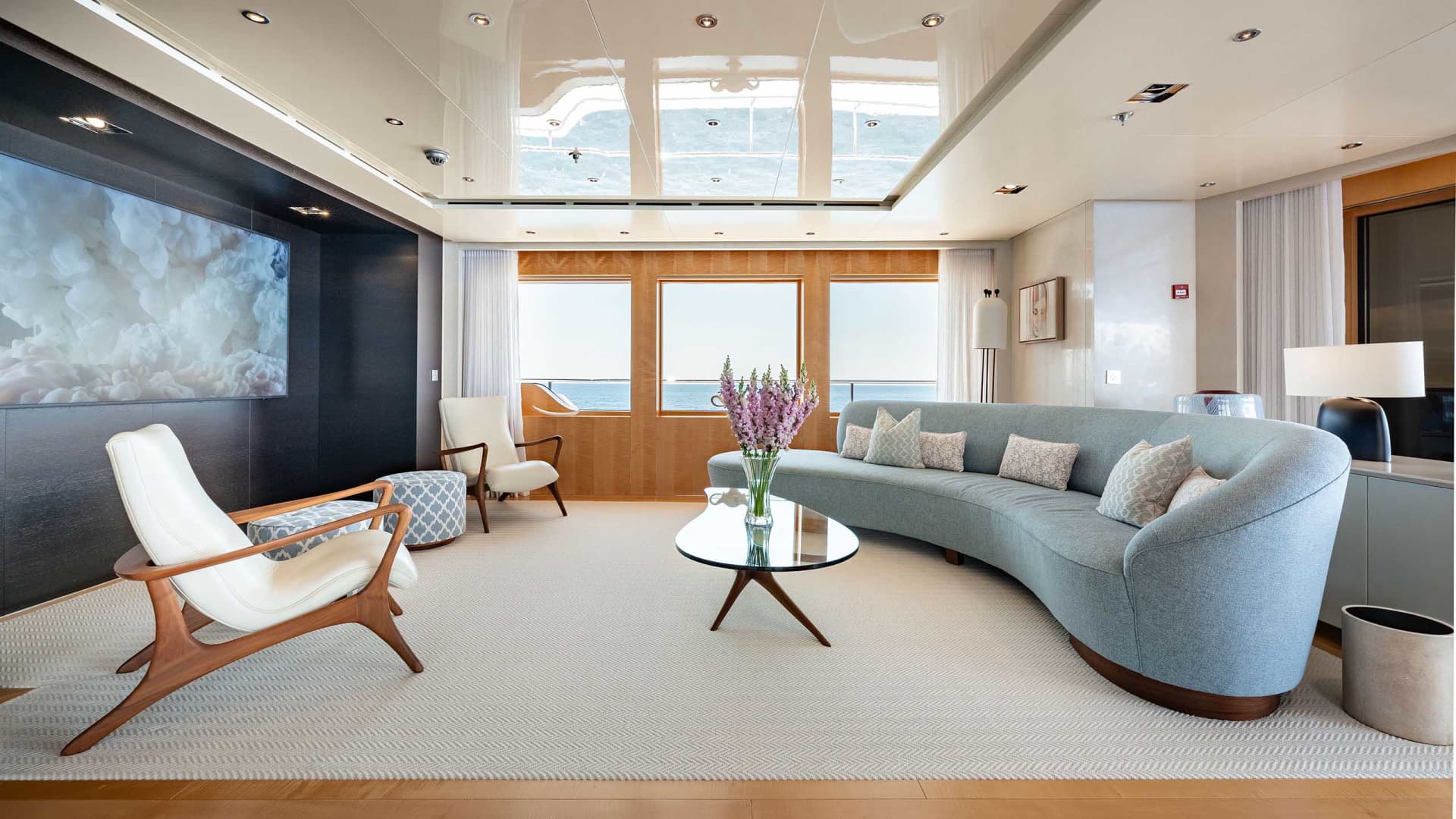 Modern residential living room featuring sofas, armchairs, and a coffee table with a vase of flowers.