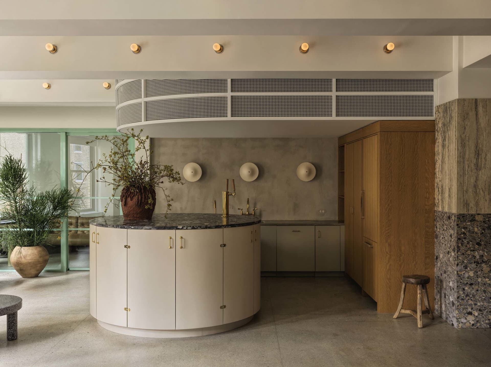 A modern residential kitchen featuring concrete walls and a round island. Shot in a contemporary interior setting.