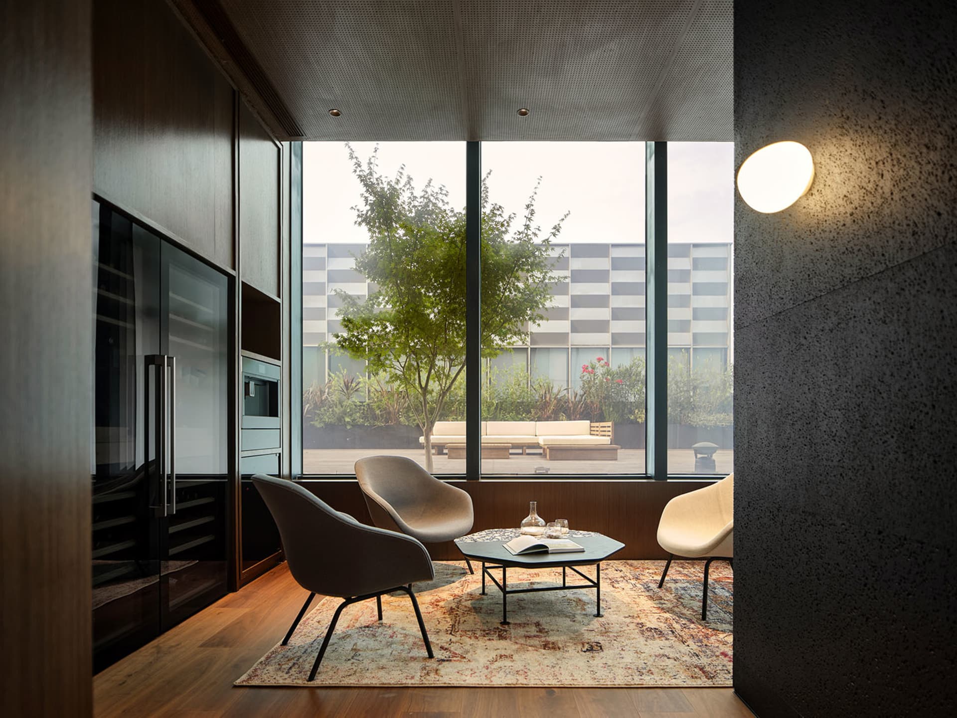 A minimalist living room featuring wooden furniture, a concrete floor, and a glass wall.