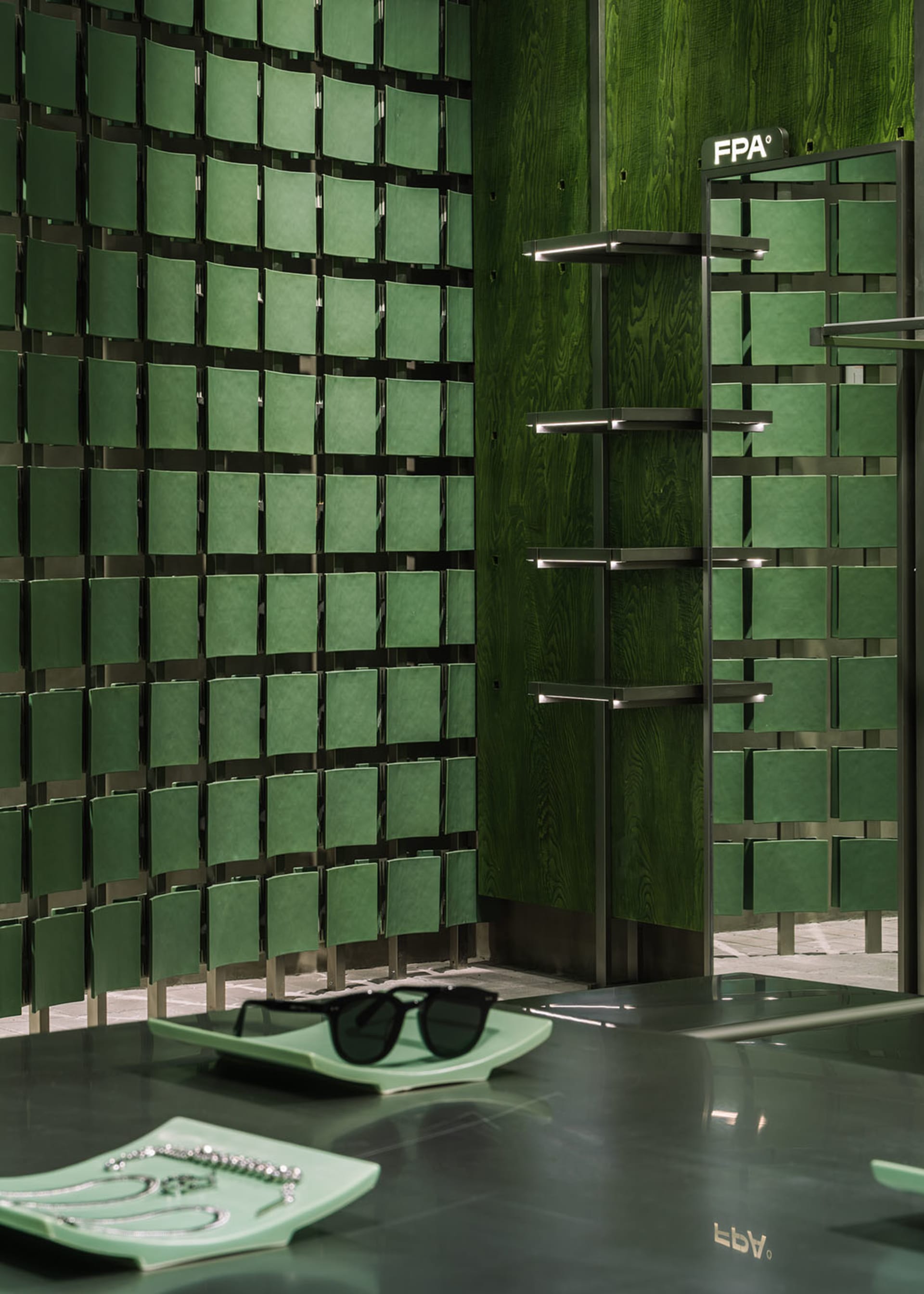 Modern retail space featuring green paneled walls and concrete furniture