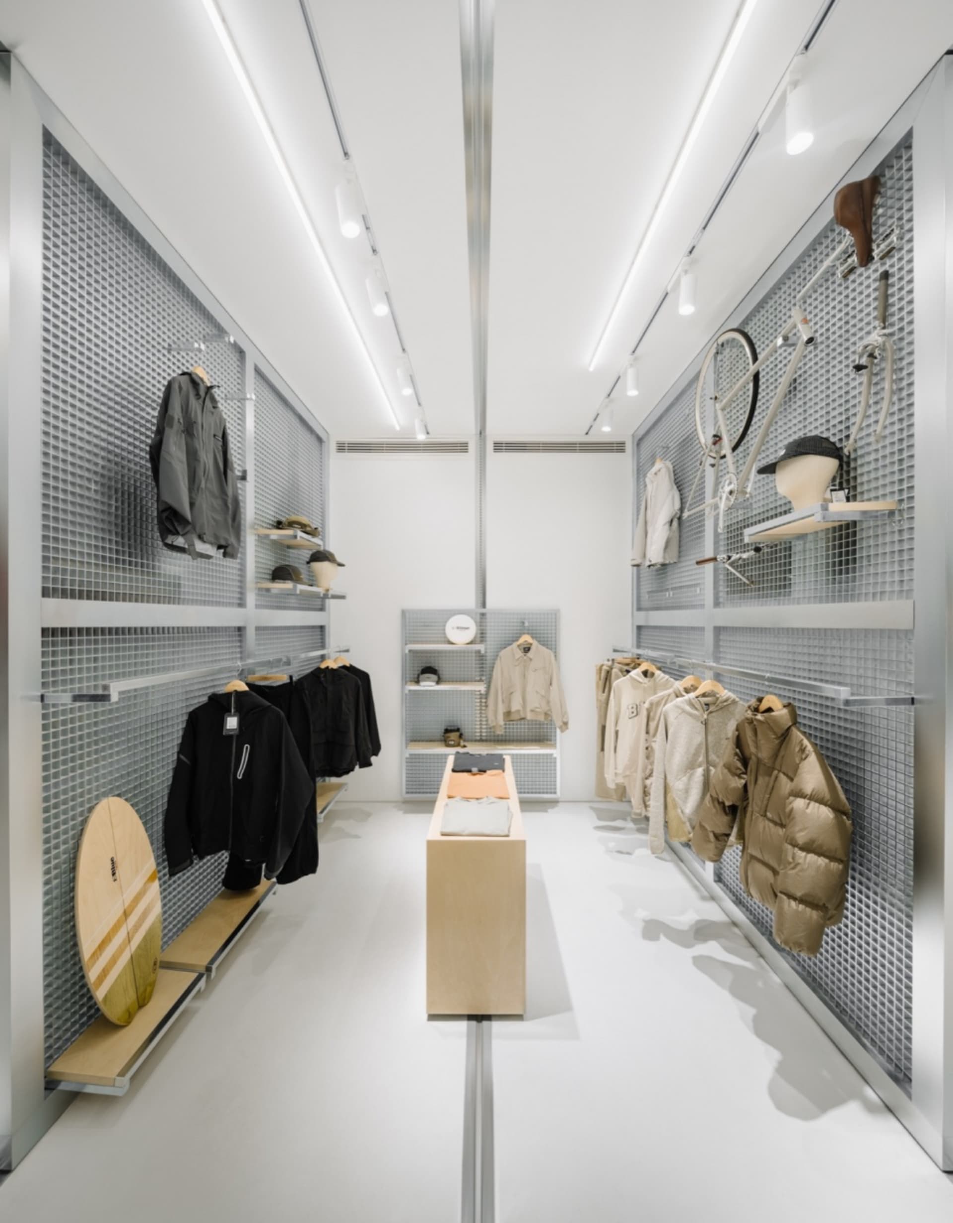 現代零售店室內,展示金屬格柵面板、木製展示家具與玻璃層板。