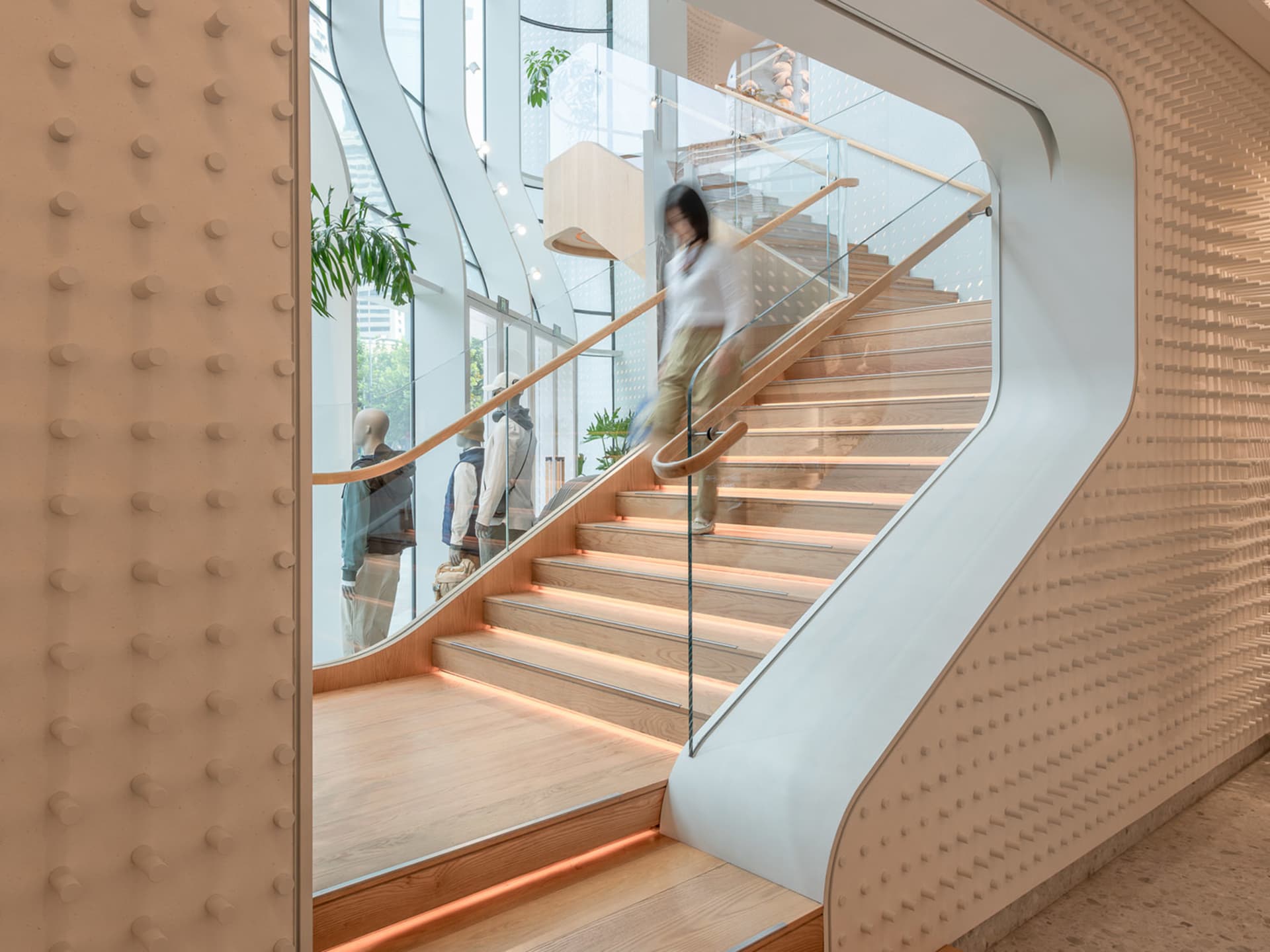 A modern retail space featuring a wooden staircase with glass railings and metal accents.