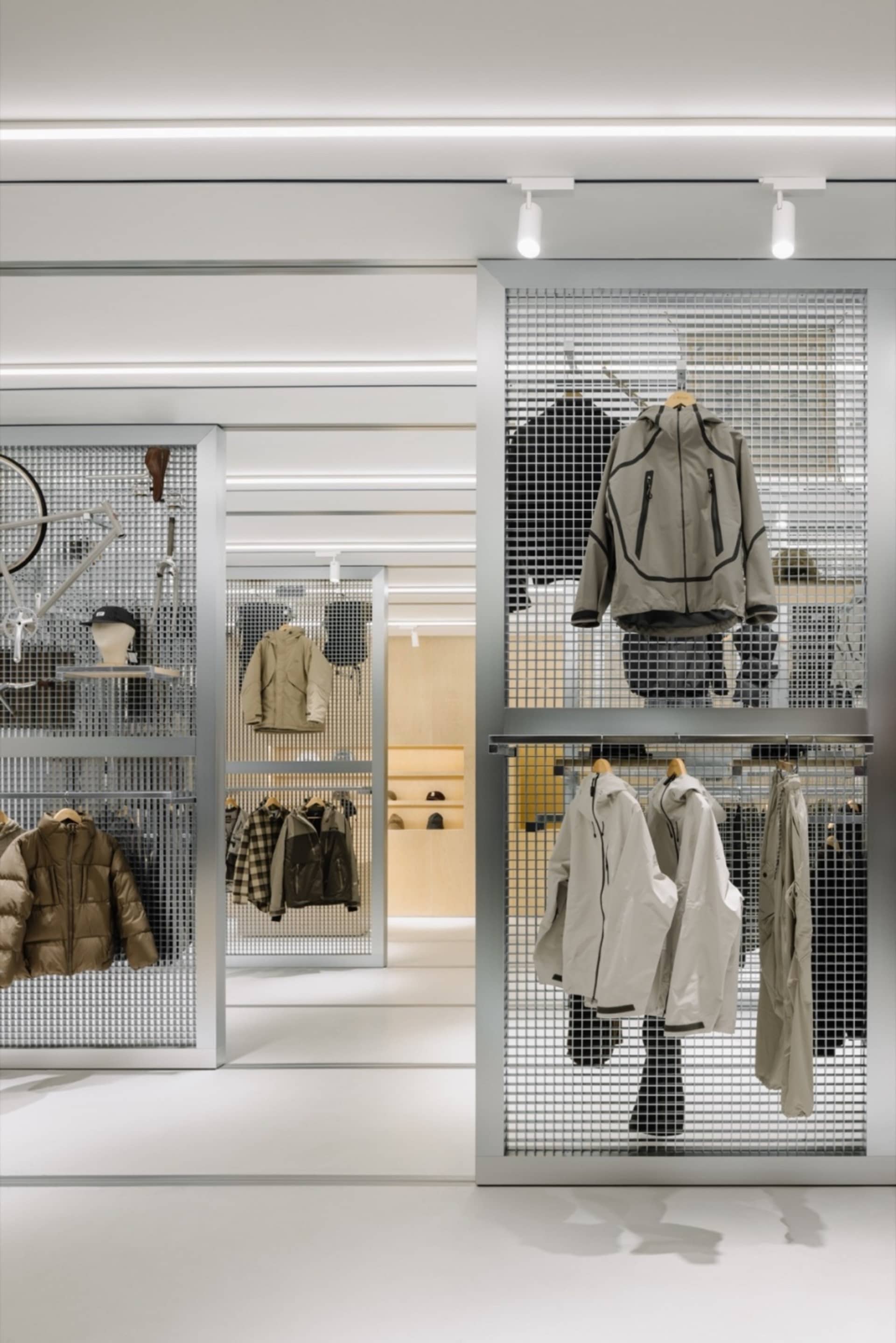 零售店面設有金屬格柵展示牆，陳列多款外套與服裝單品。