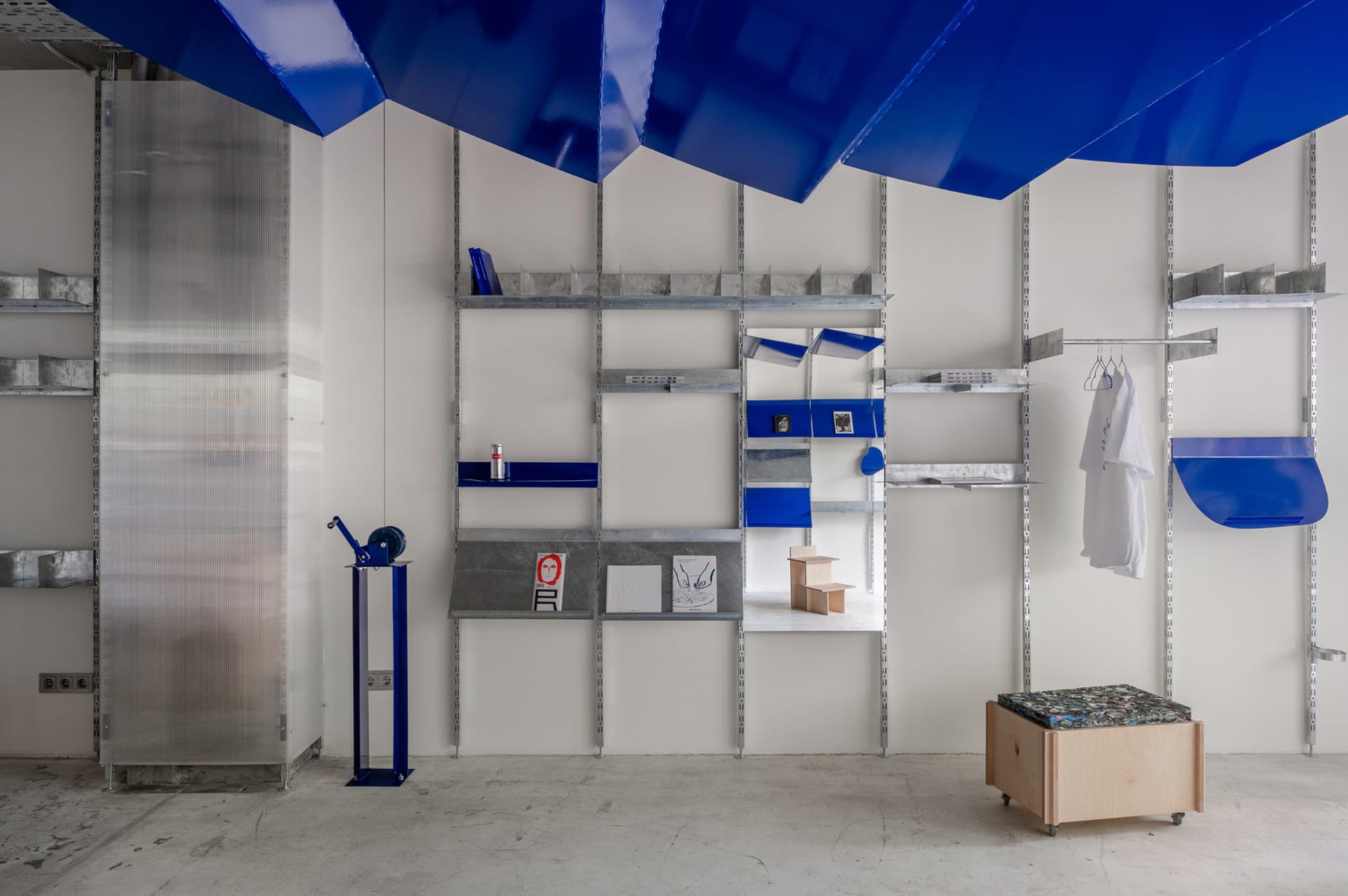 A minimalist workspace featuring metal shelving units and a blue canopy.