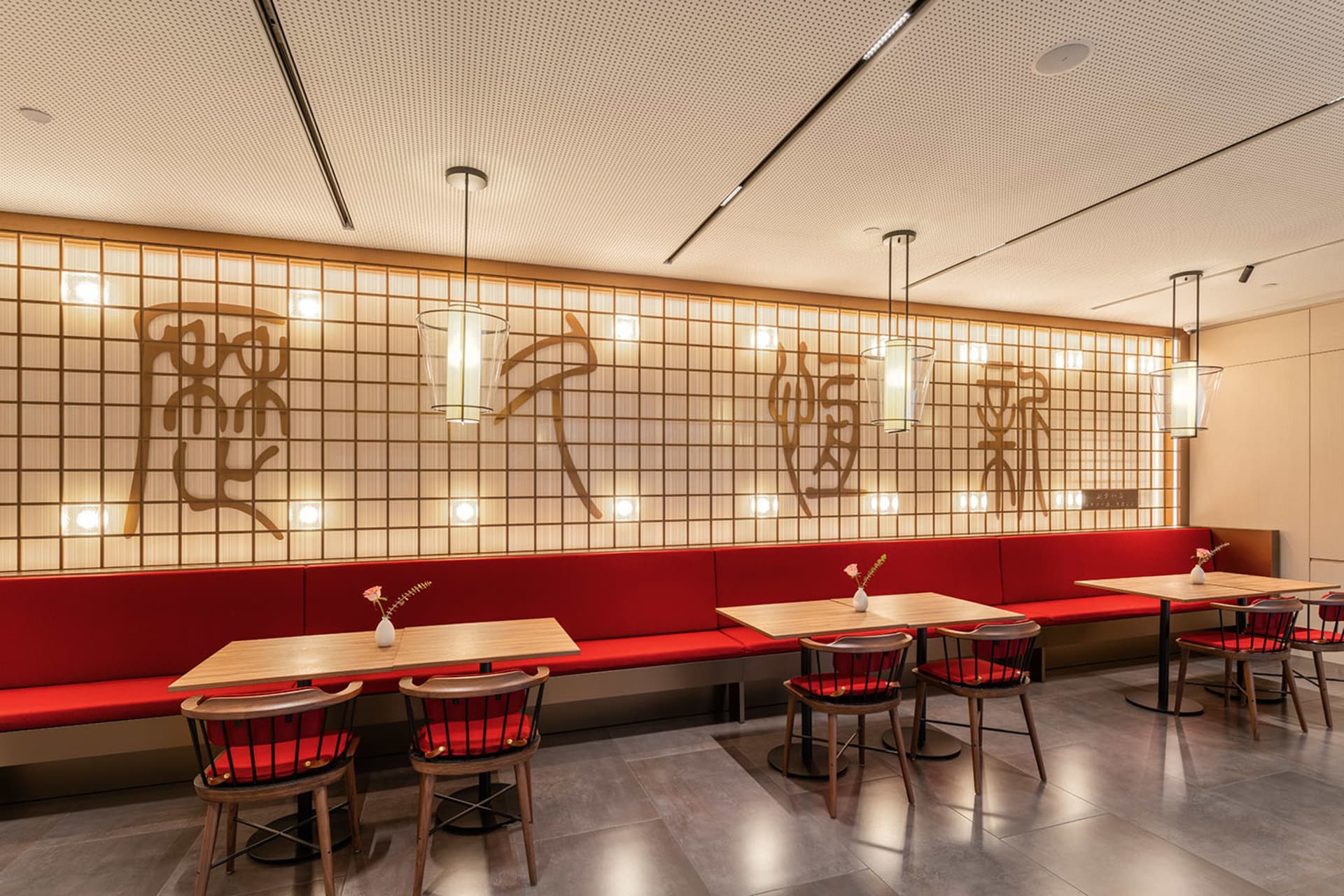 Modern, red-themed restaurant interior with wooden furniture and decorative lighting.