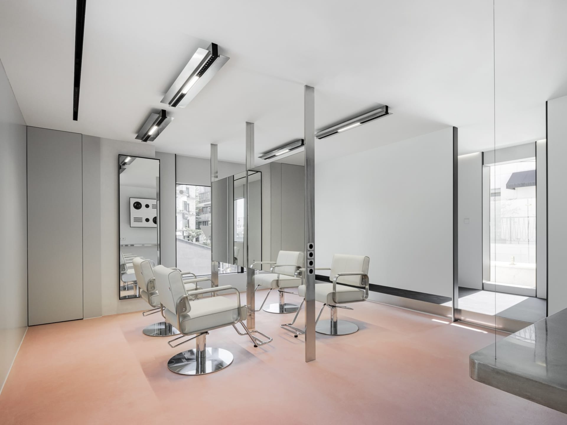 Modern, minimalist salon interior with metallic furniture and large mirrors.