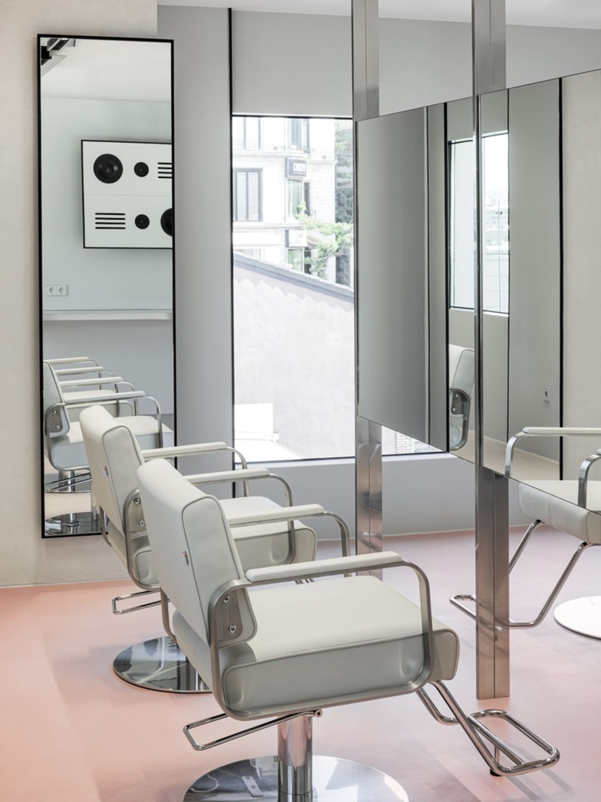 A modern commercial space featuring white leather chairs and mirrors.