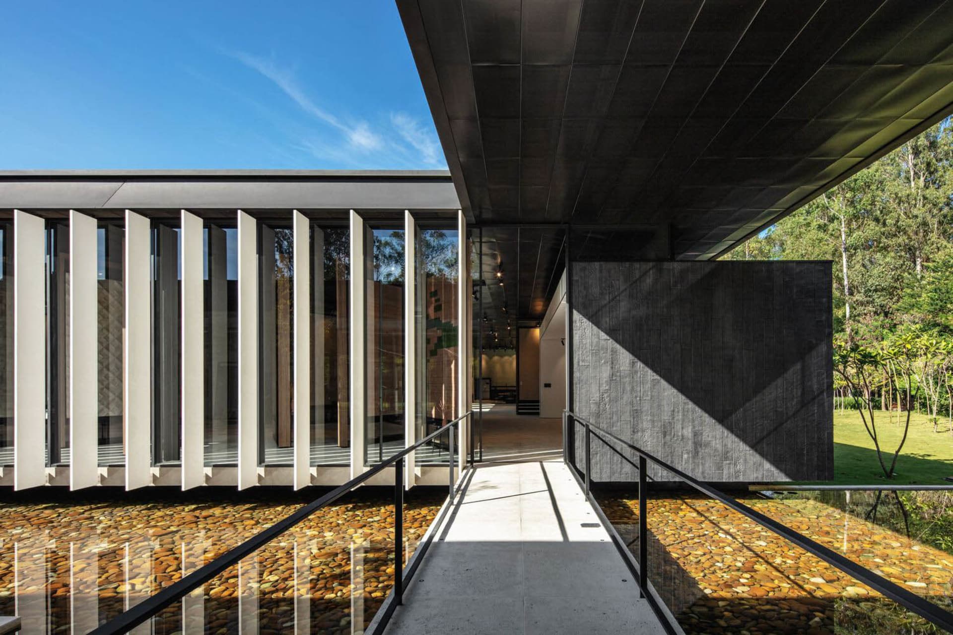 A modern minimalist house with metal, concrete, and glass exterior materials.