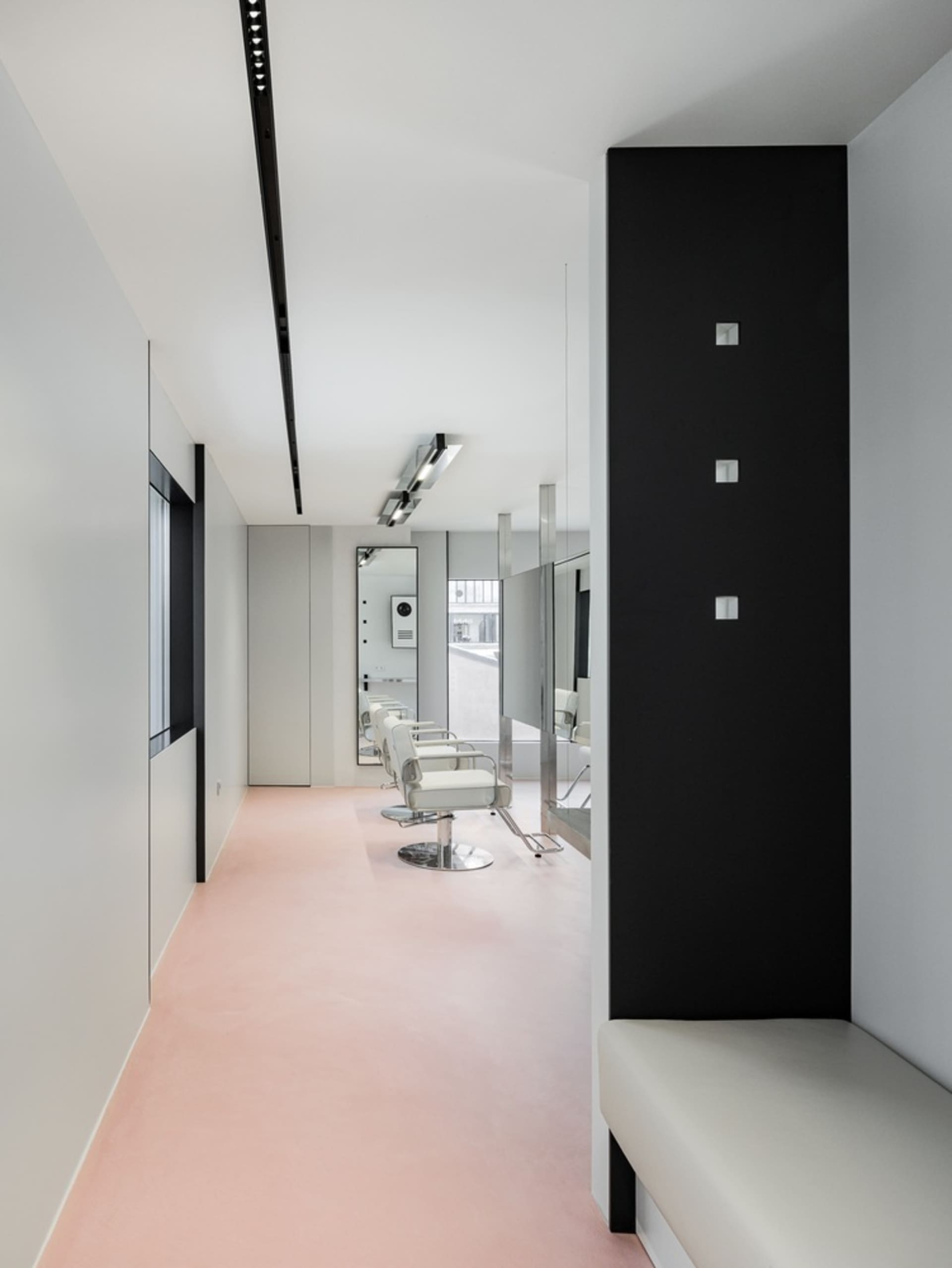 Modern hair salon interior with minimalist design and white concrete floor.