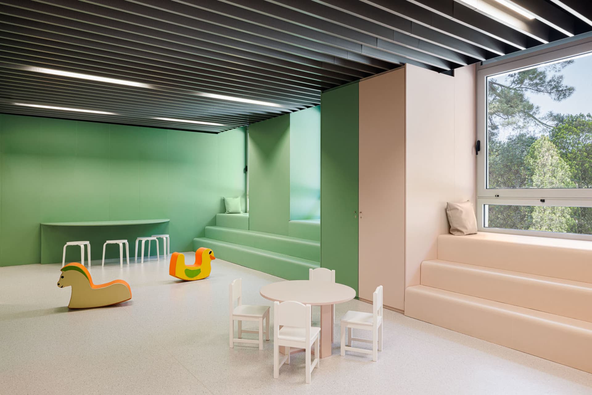 A modern child playroom features soft, green, and white materials and furniture.