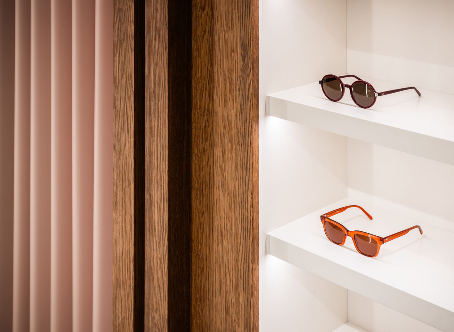 Pair of sunglasses on white wooden shelves in a retail display setting.