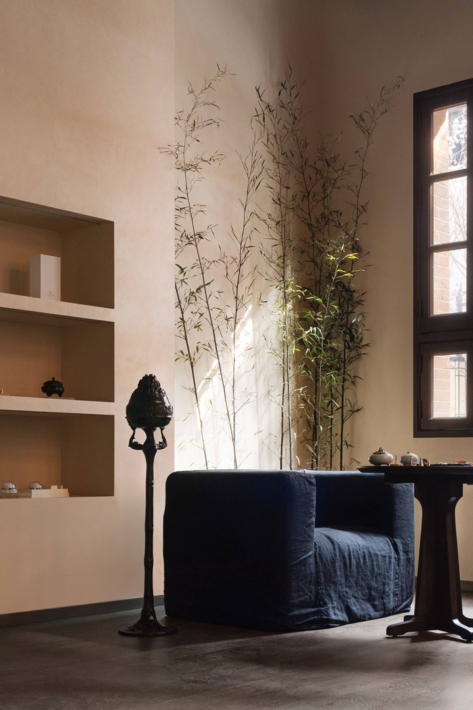 Modern living room with wooden sofa and shelves, natural light, and green plants.