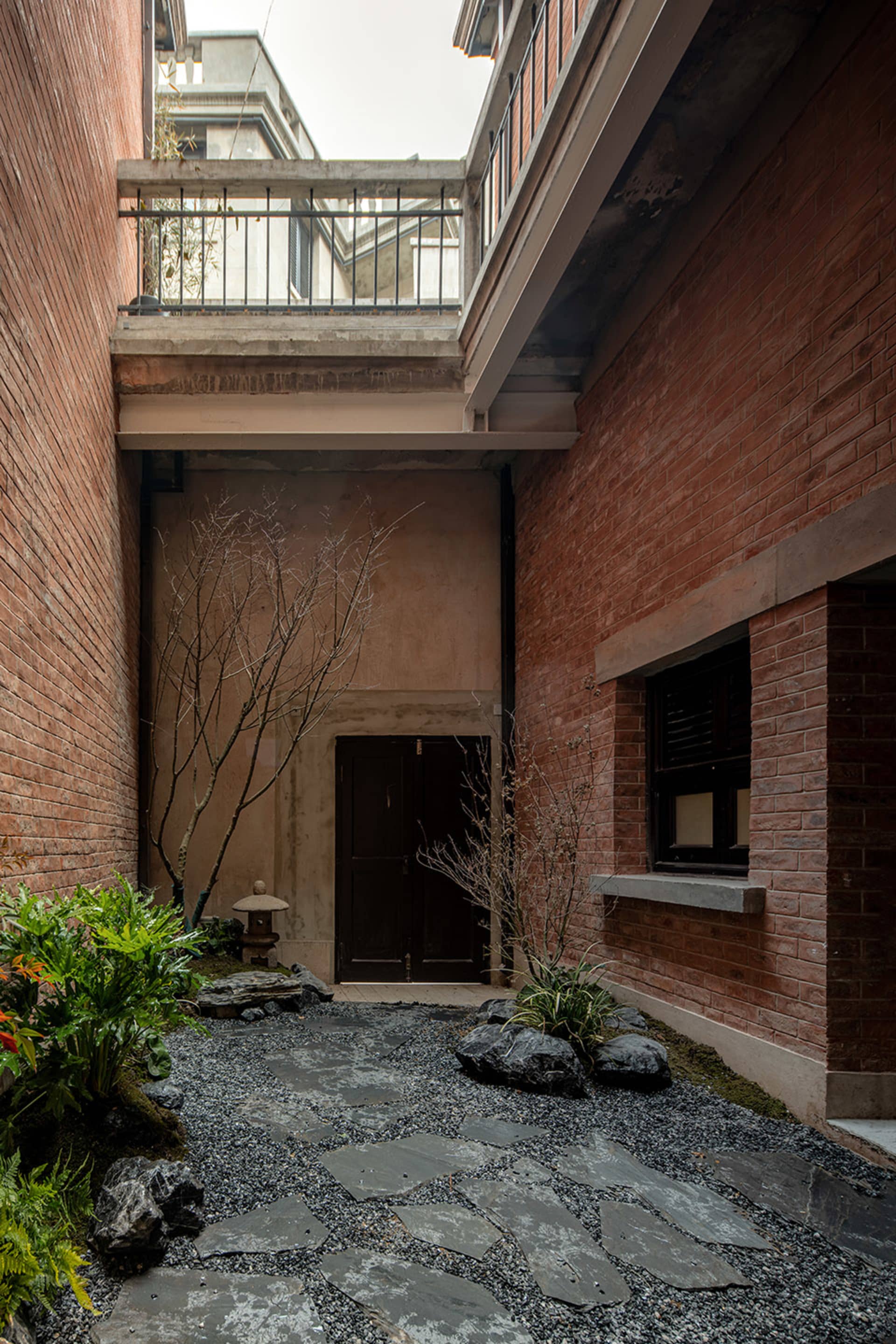 Concrete garden with rock formations and a modern entrance door.