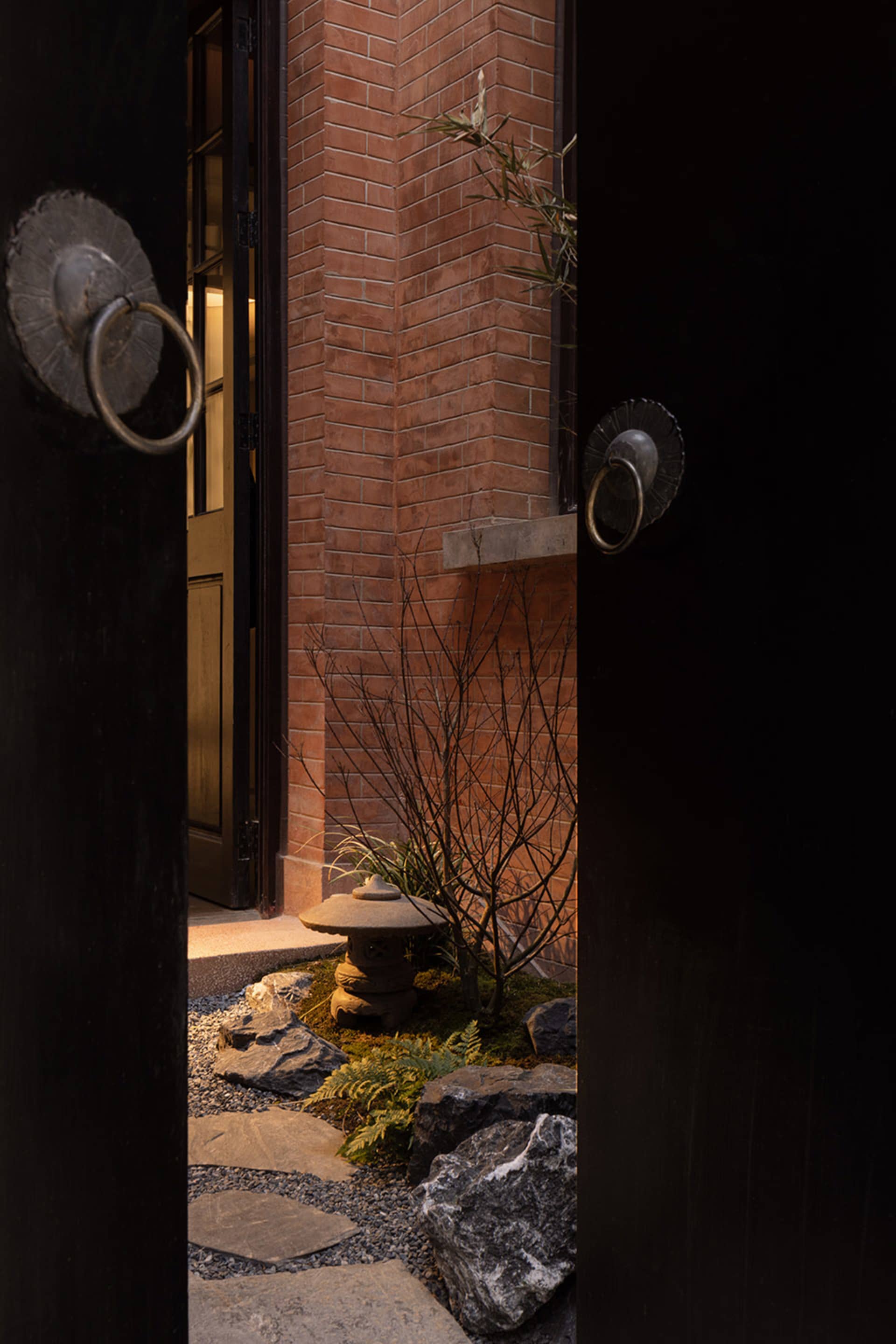A traditional entrance with stone and brick elements, including a doorknob, pathway, and plant.