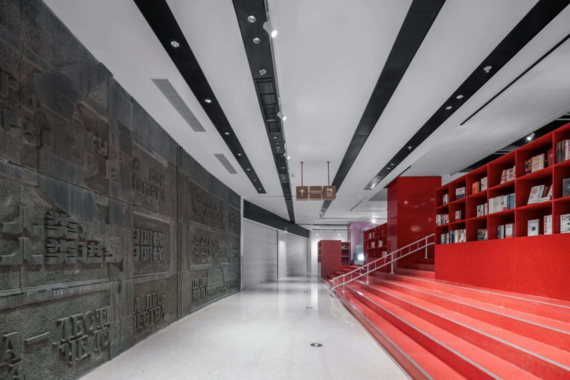 A modern library with red shelving units and concrete walls.