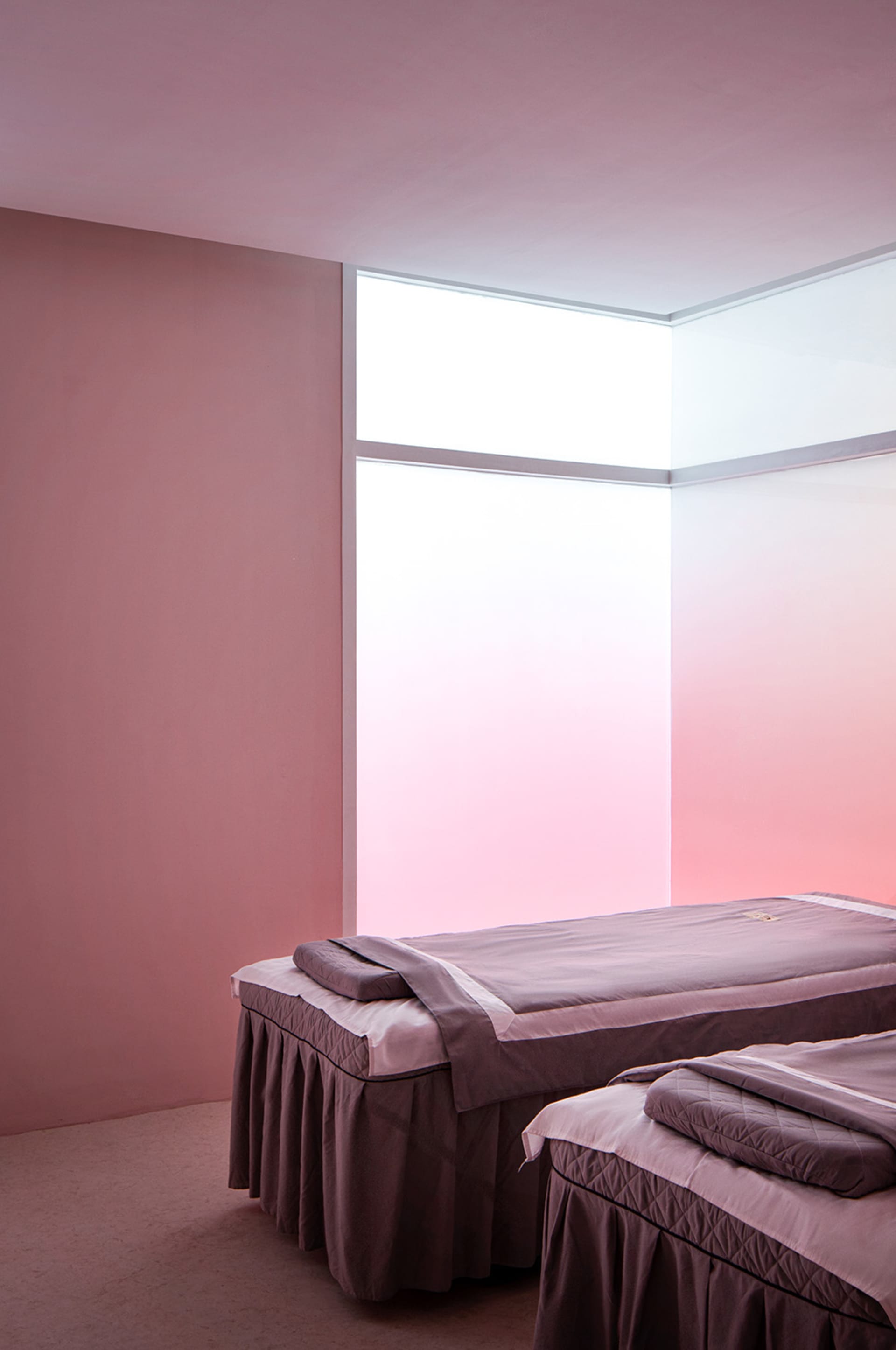 A minimalist bedroom featuring purple fabric beds under a frosted glass window.