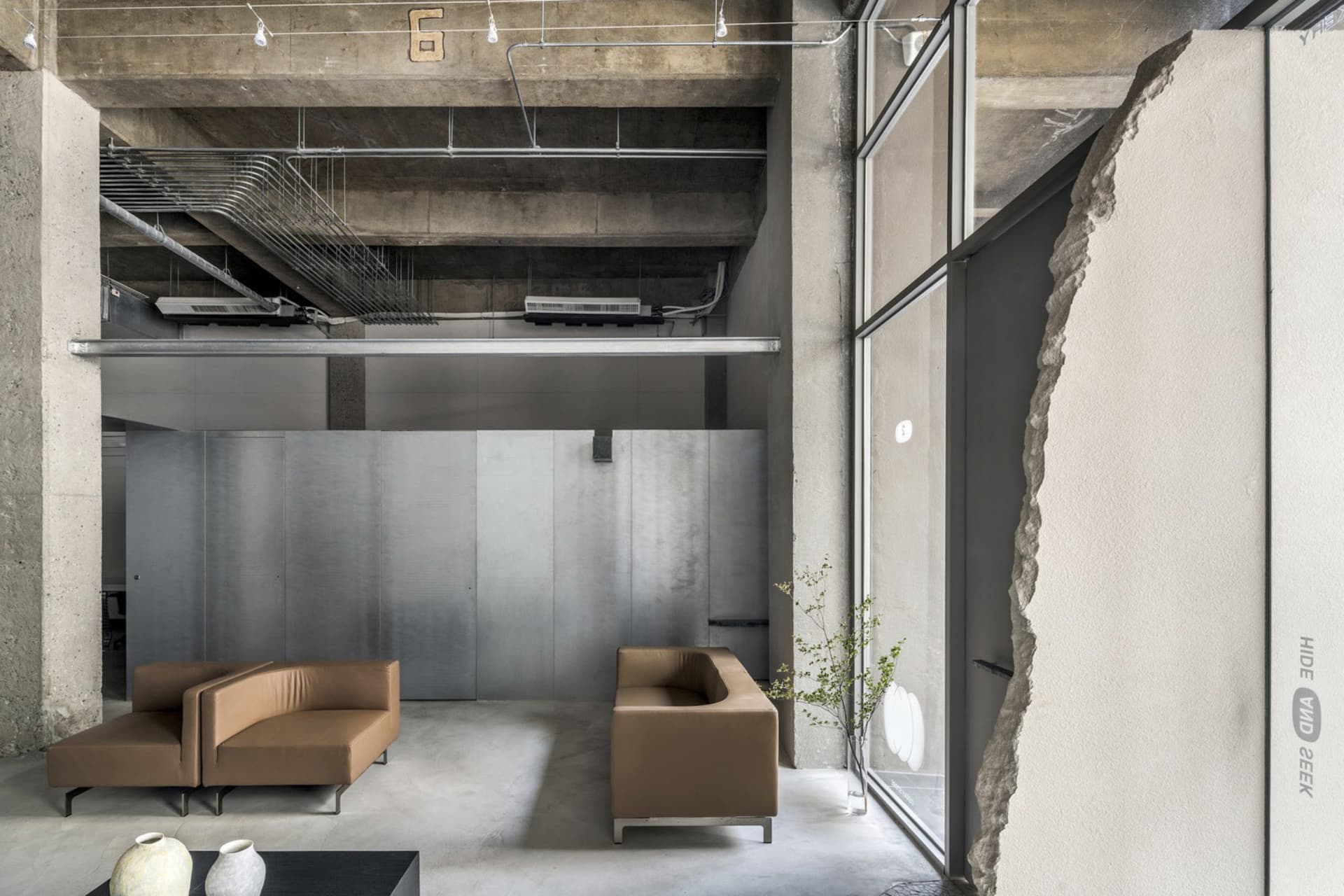 Industrial modern office interior with concrete, metal, and leather furniture.