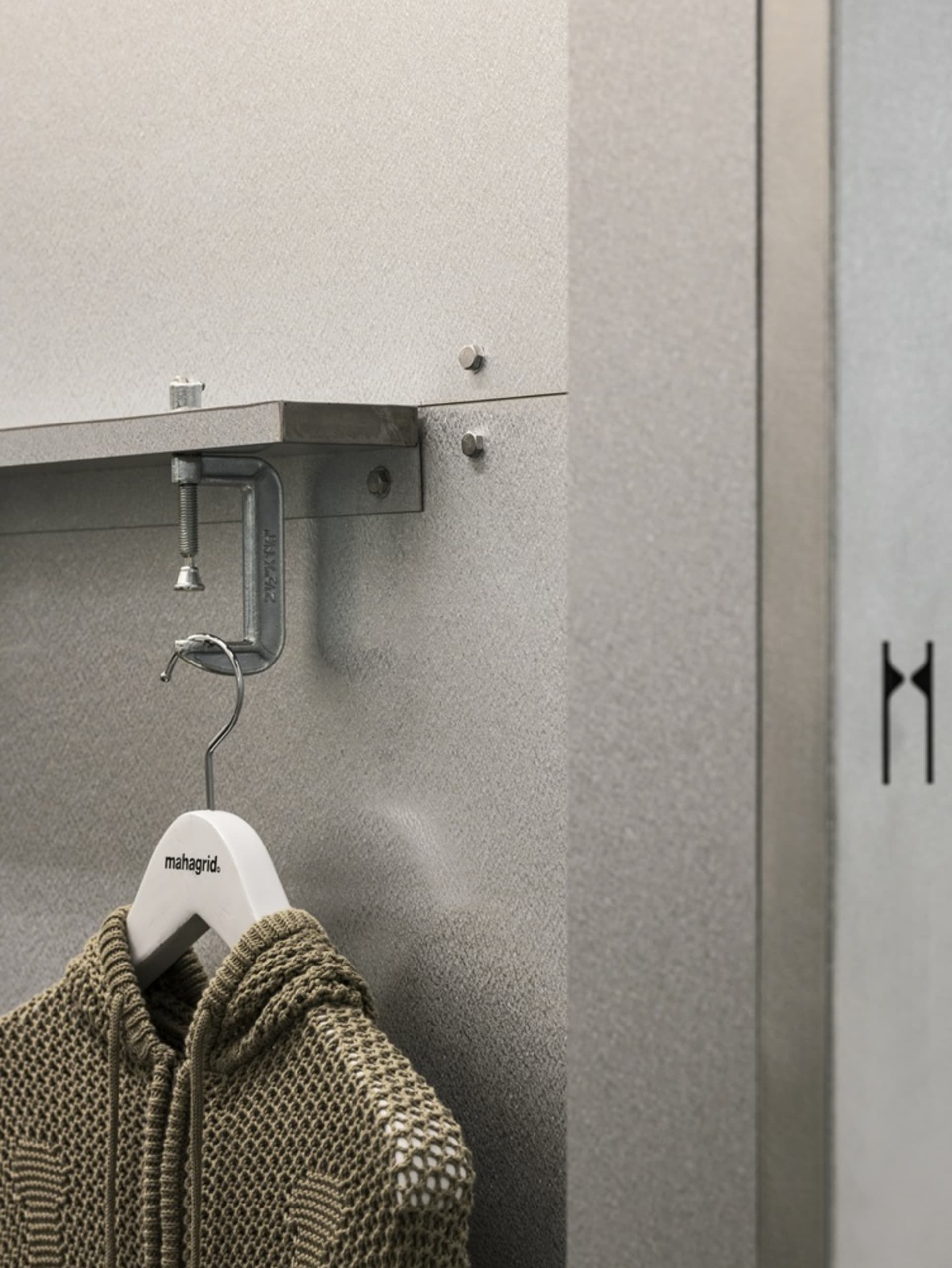 Clothing hooks hanging on a metal shelf in a storage area.