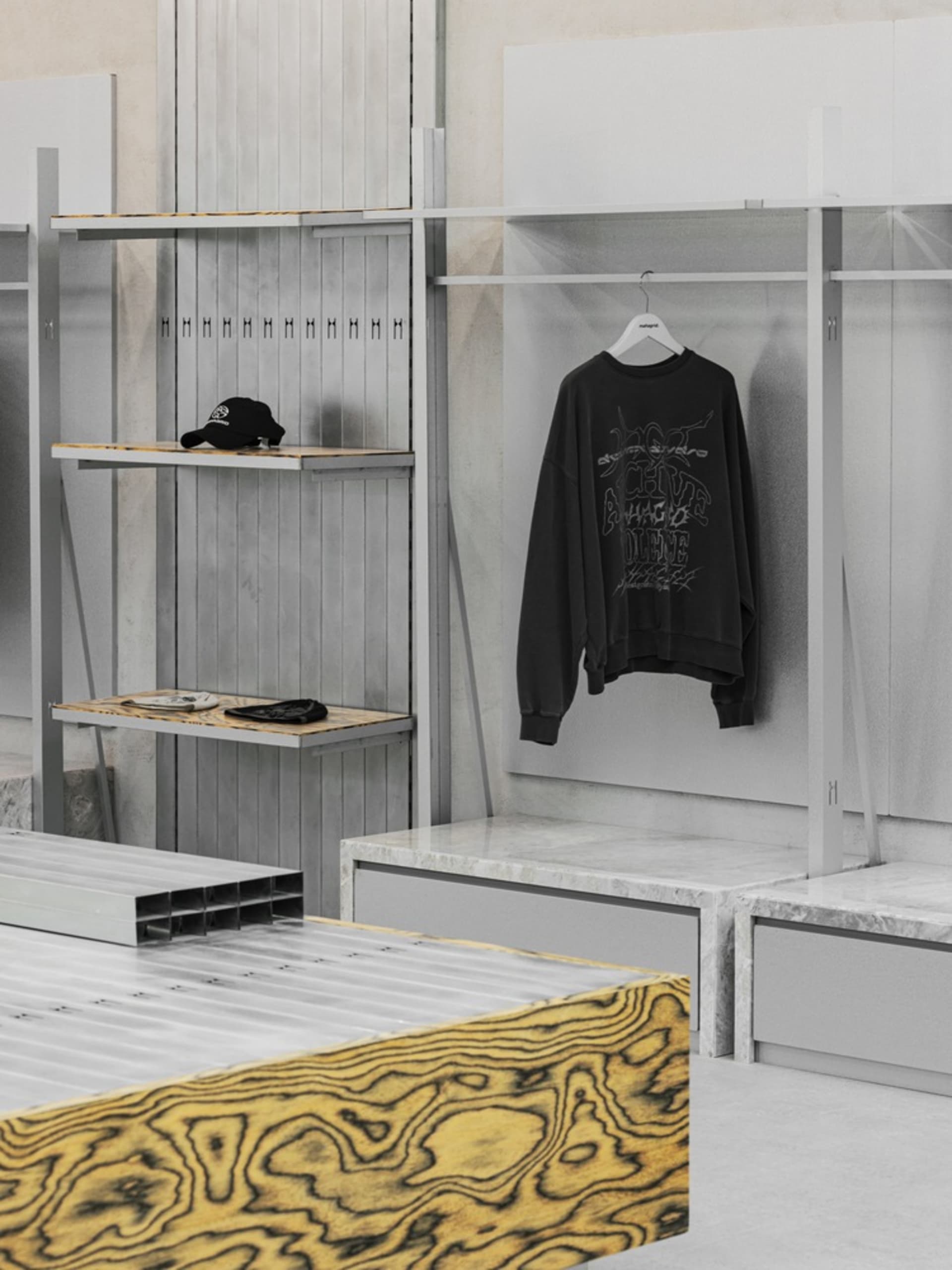 A minimalist clothing retail display featuring industrial-style metal shelves and marble countertops.