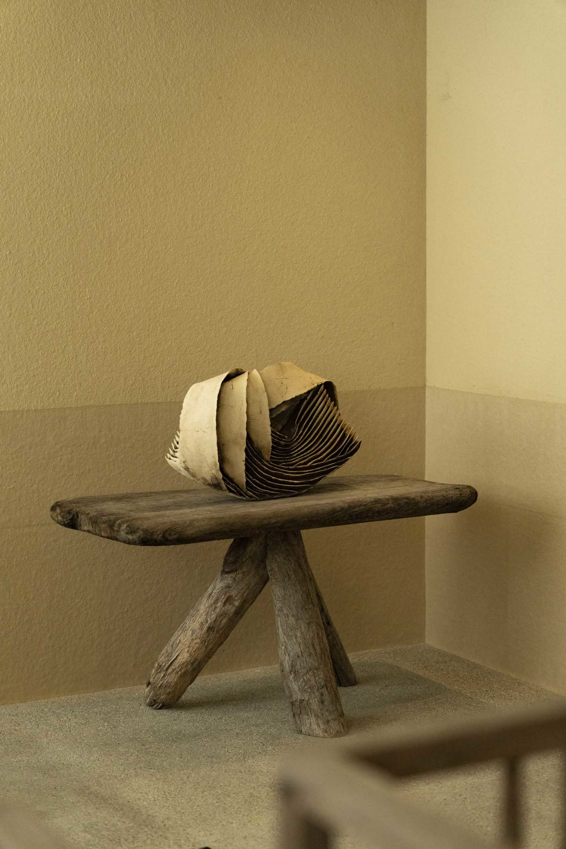 A minimalist wooden chair with a unique, folded seat design.