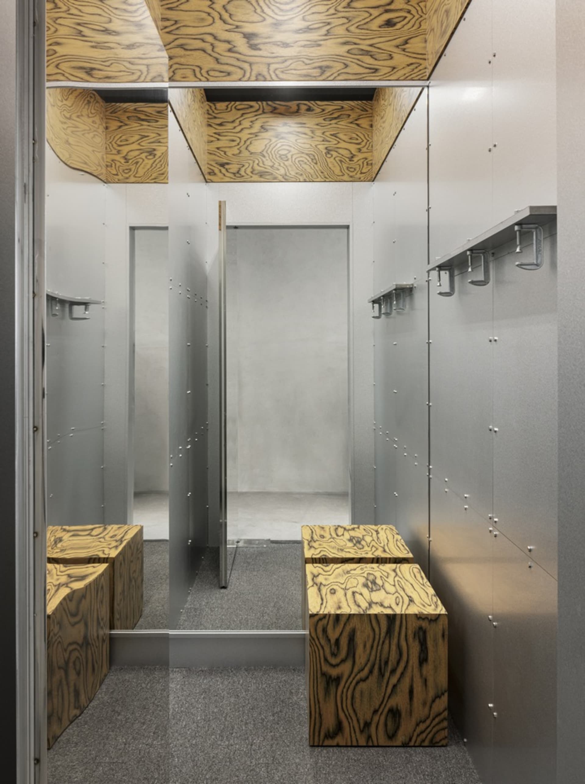 Modern industrial clothing store vestry with wood-grain panels and metallic accents