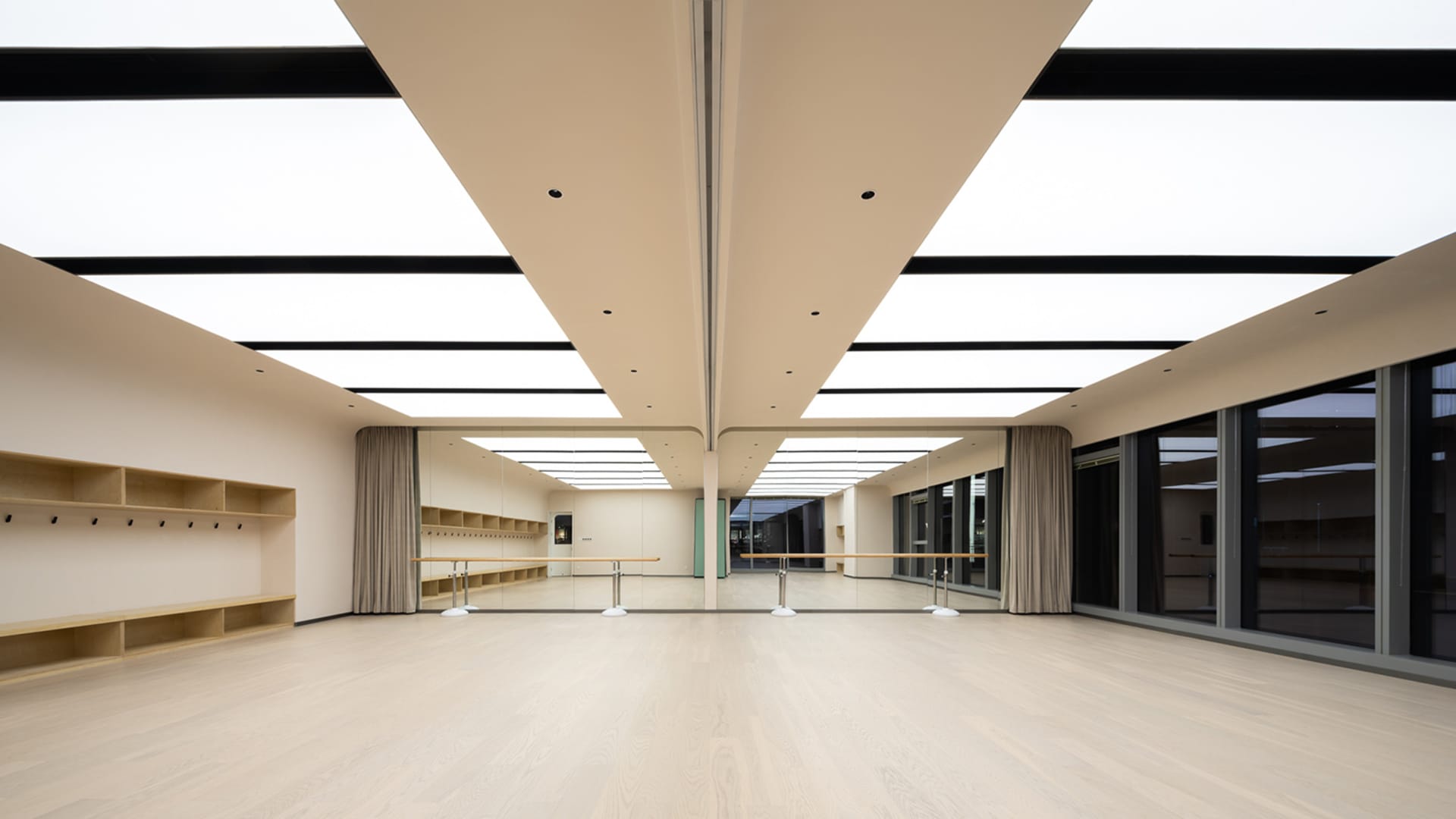 Modern dance studio with wooden floor, glass curtains, and large windows.