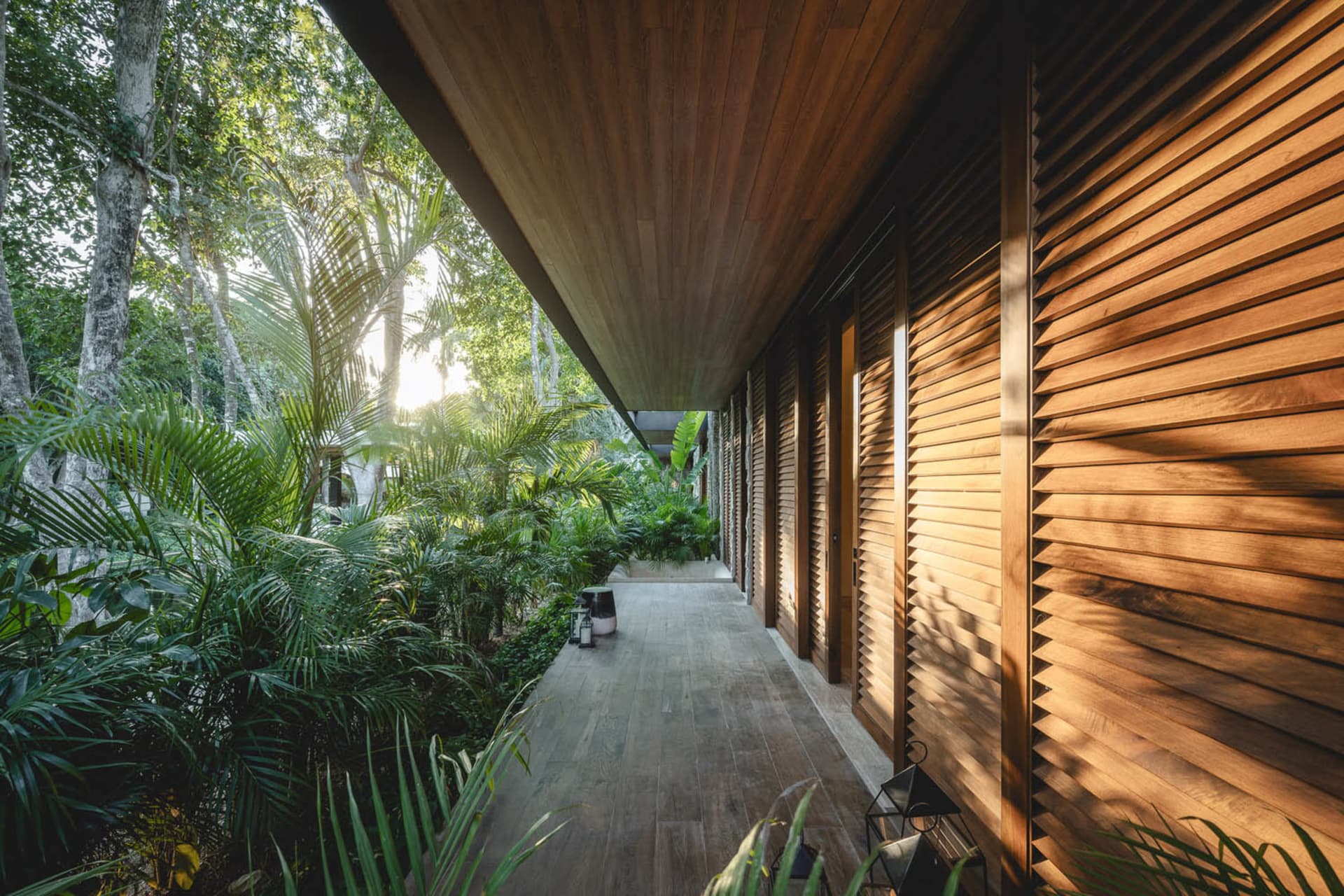A modern house exterior with tall wooden shutters and lush greenery in the background.
