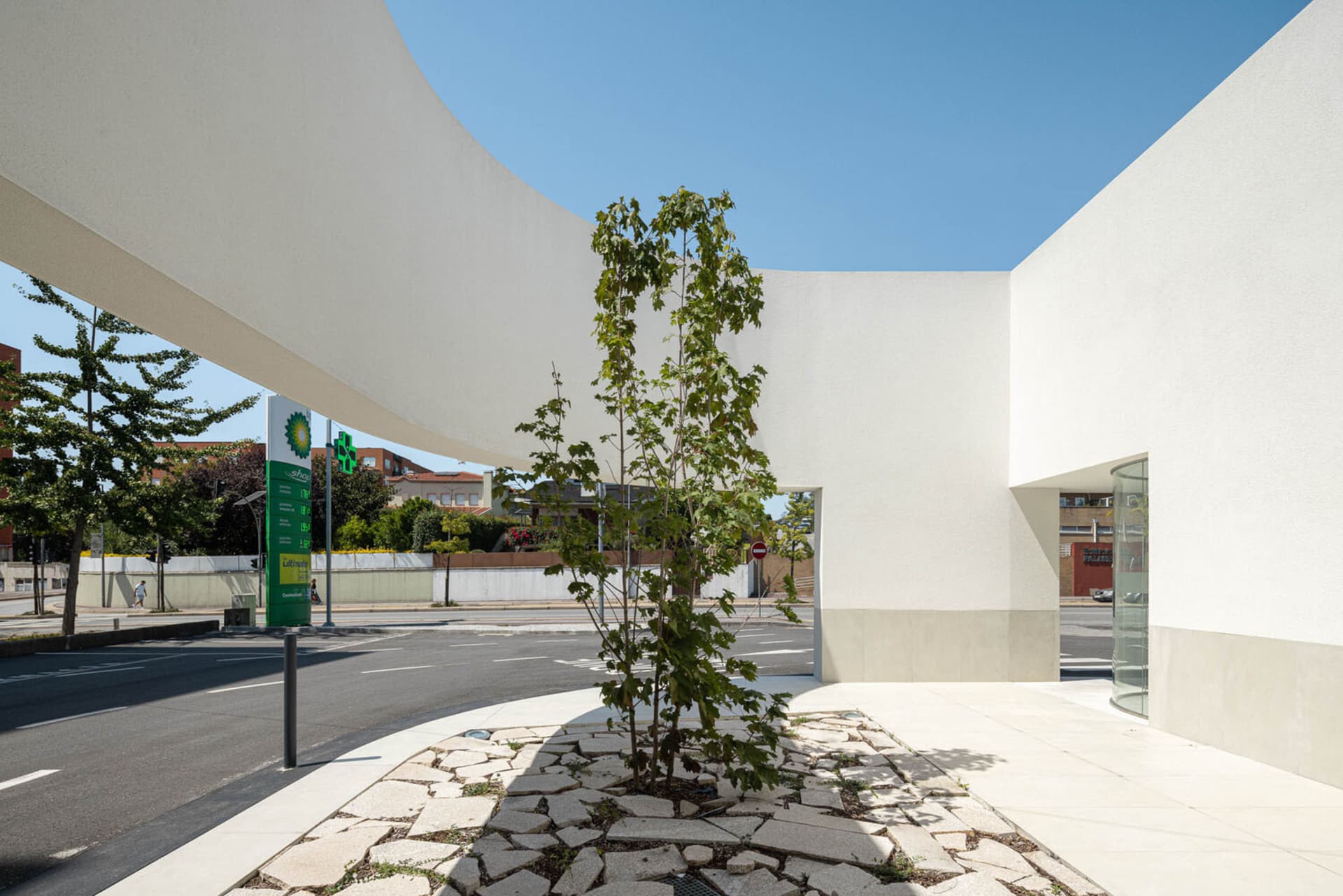 A modern retail storefront with a concrete facade lined by a cracked cobblestone sidewalk and a large white rectangular canop
