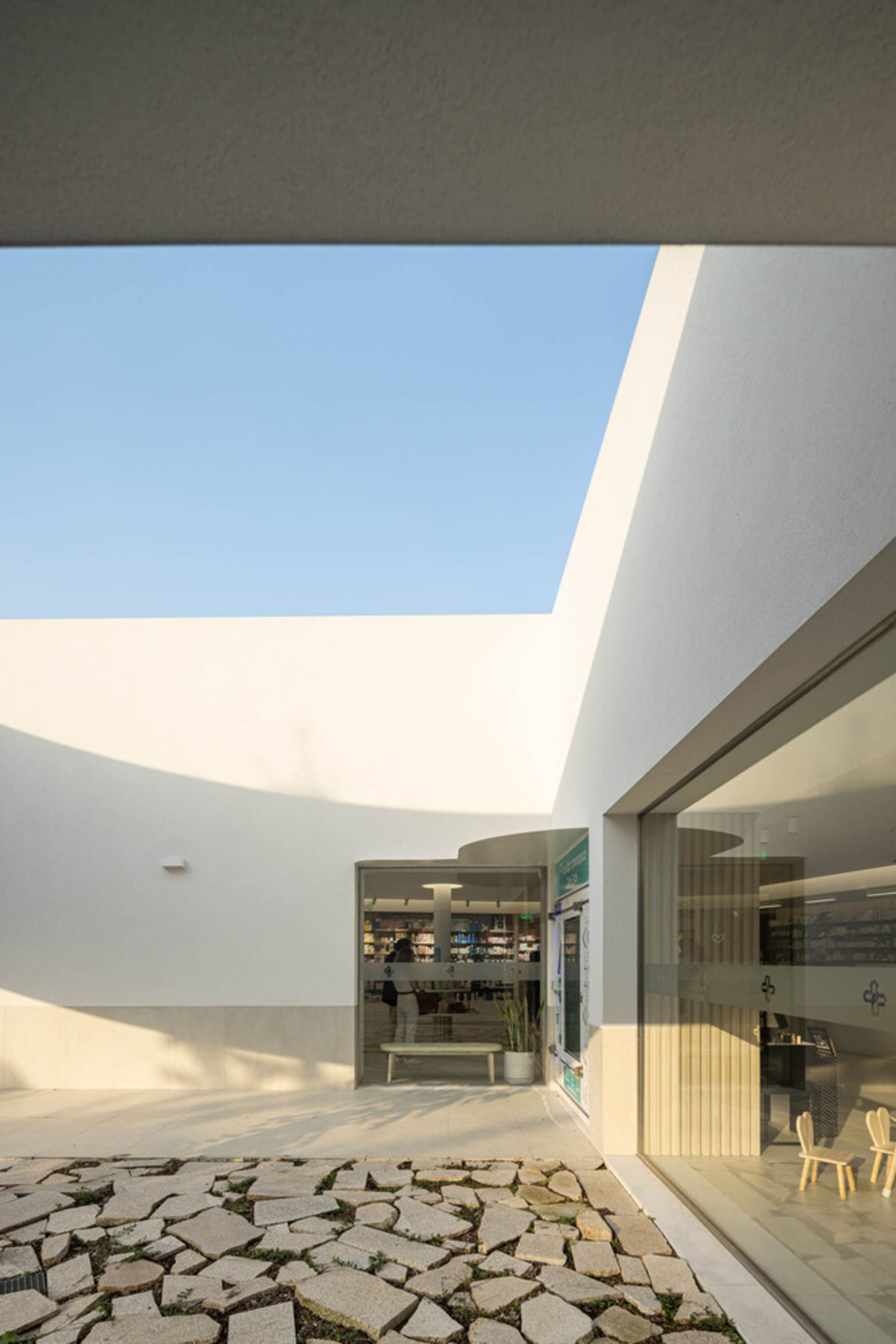 A modern storefront with glass walls, featuring a skylight and an open courtyard.