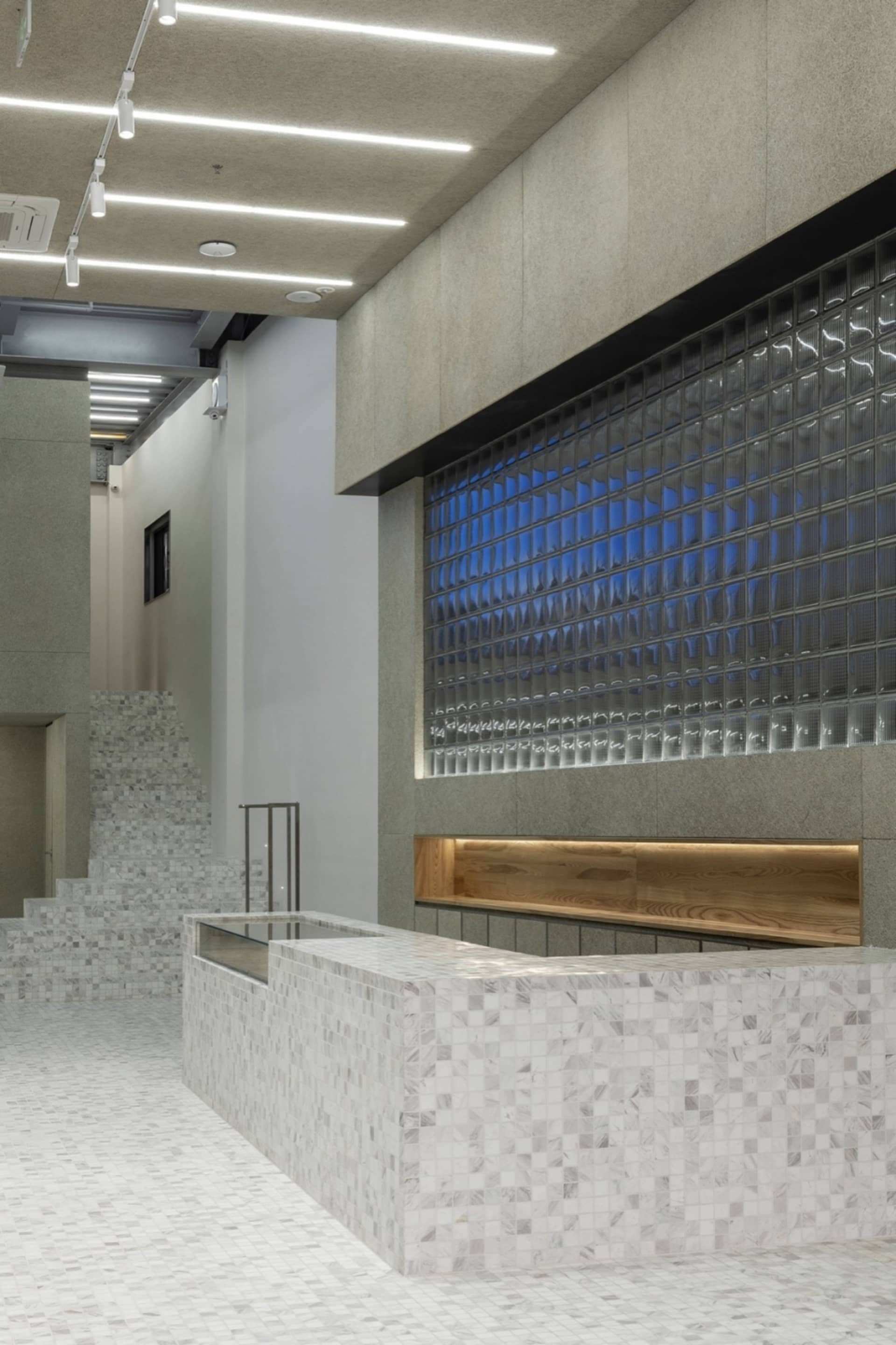 A modern reception desk made of concrete with glass inserts and a wooden counter.