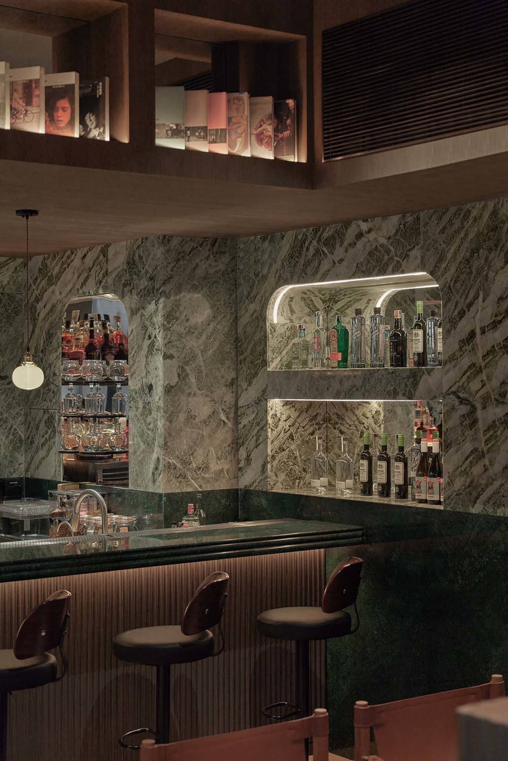 A modern industrial-style bar interior with a marble counter and stools.
