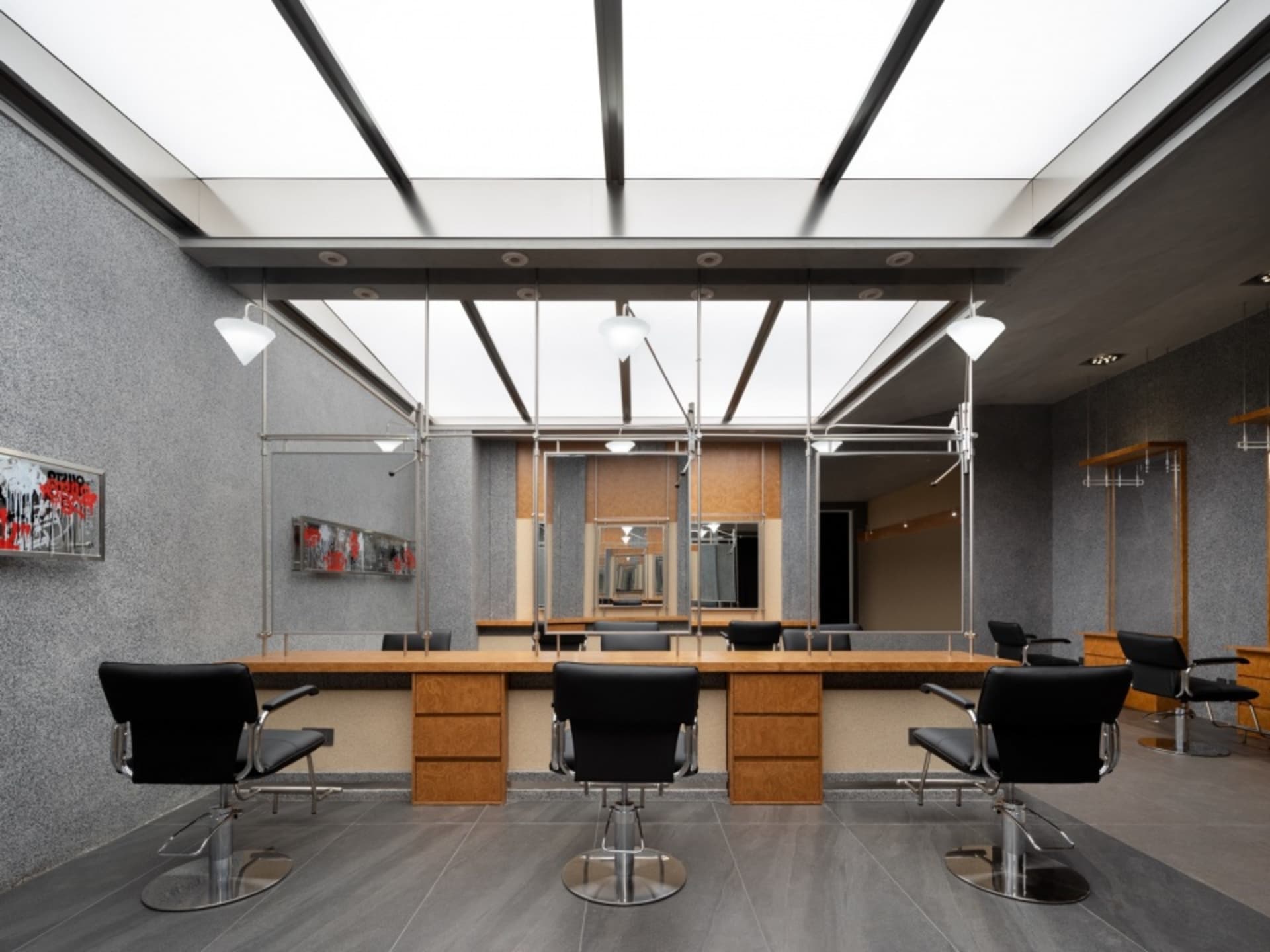Modern, minimalist salon interior with black chairs, wooden countertops, and metal accents.