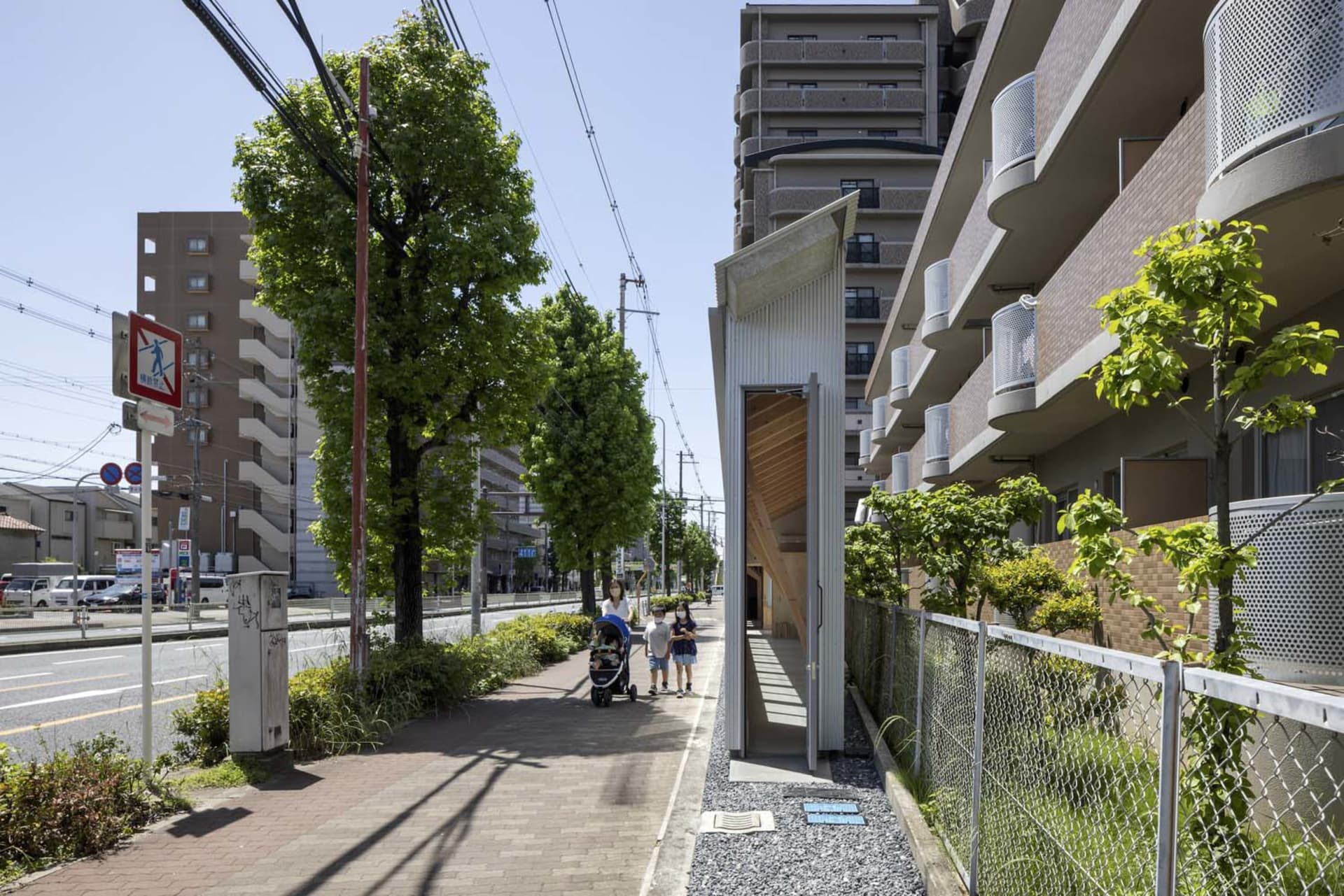 Urban landscape with a modern street view featuring a concrete pathway, residential buildings, and greenery.