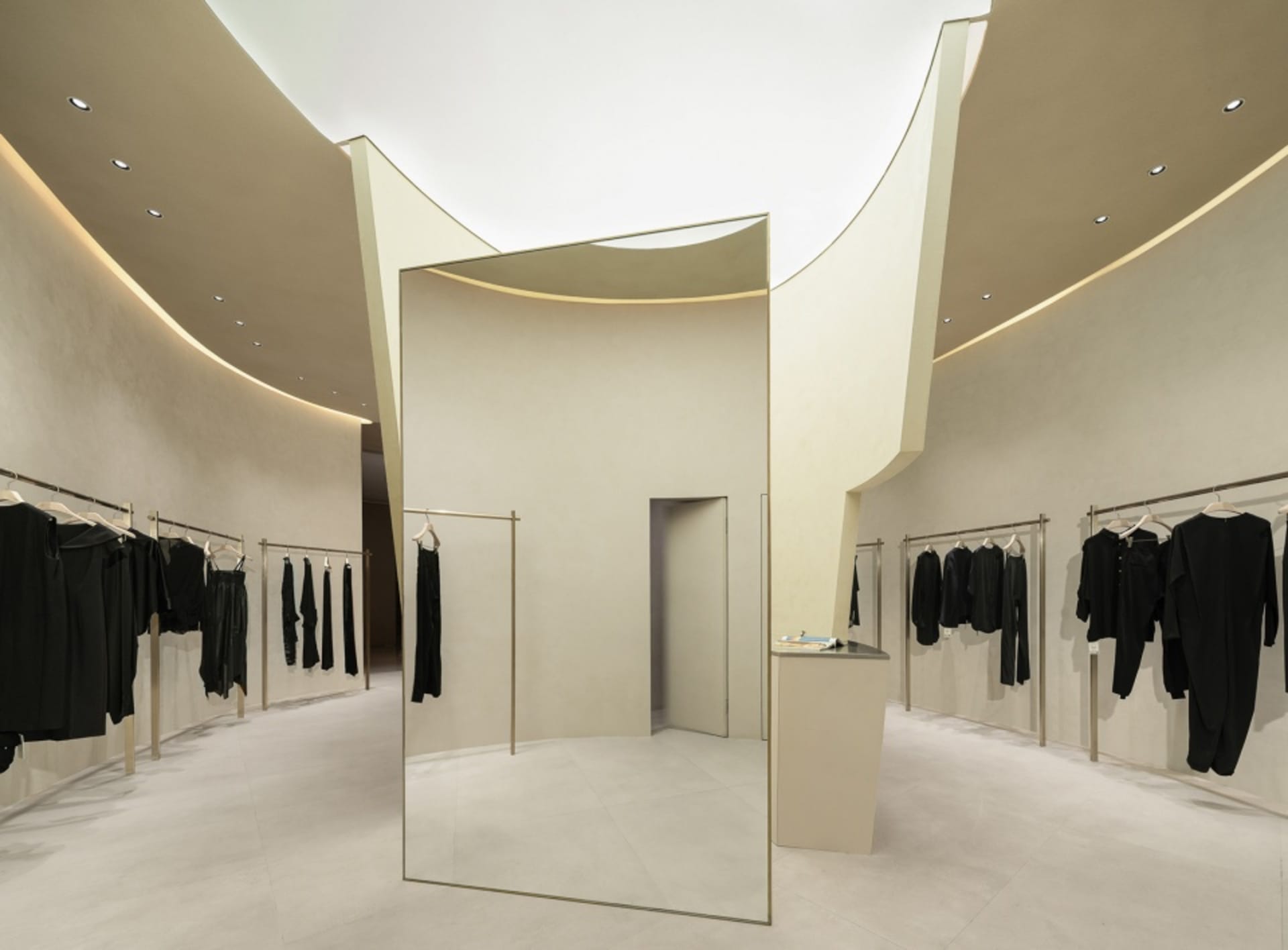 Minimalist fashion retail store with white reflective surfaces and neutral tones
